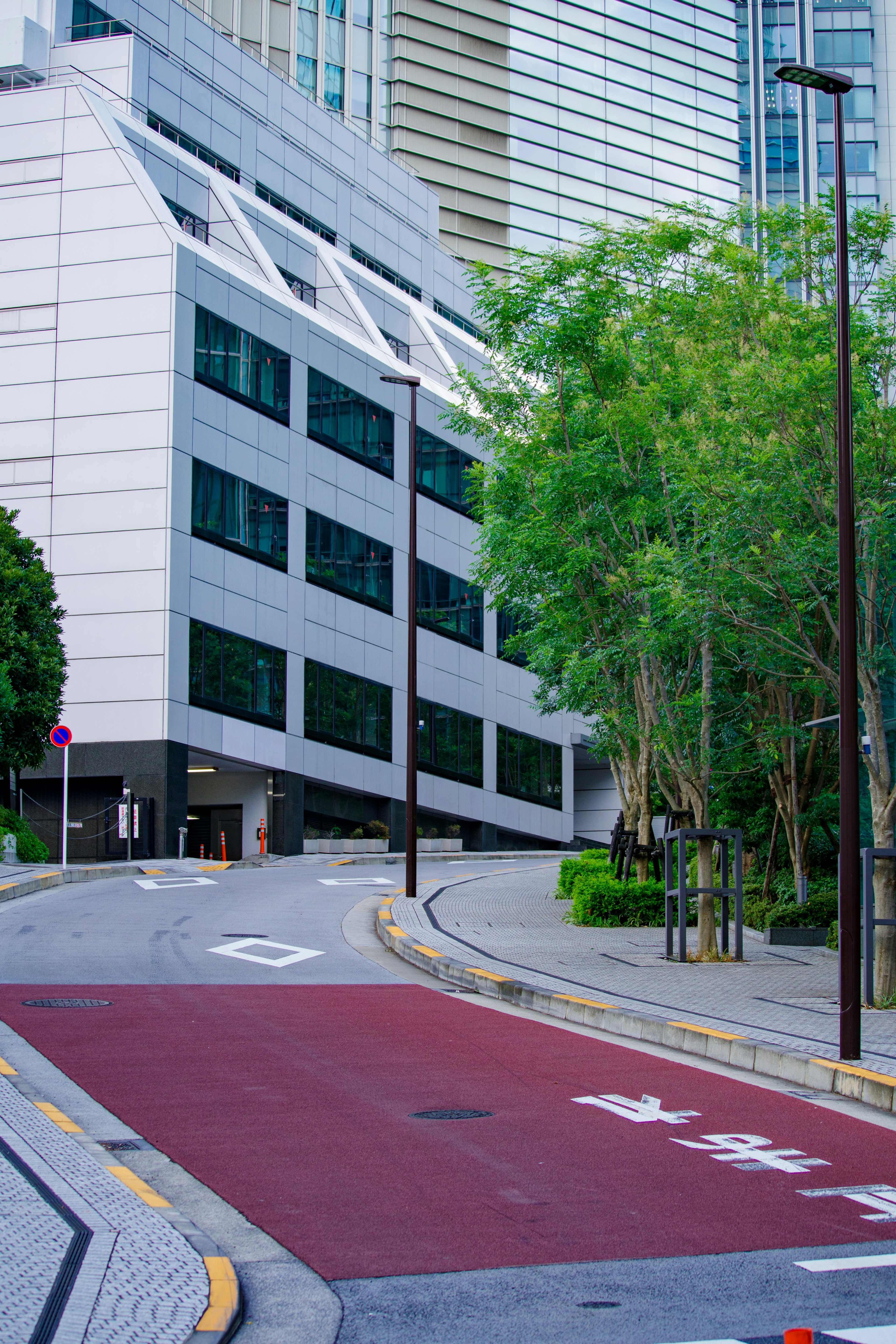 Image of a sloped road with a modern building and green trees