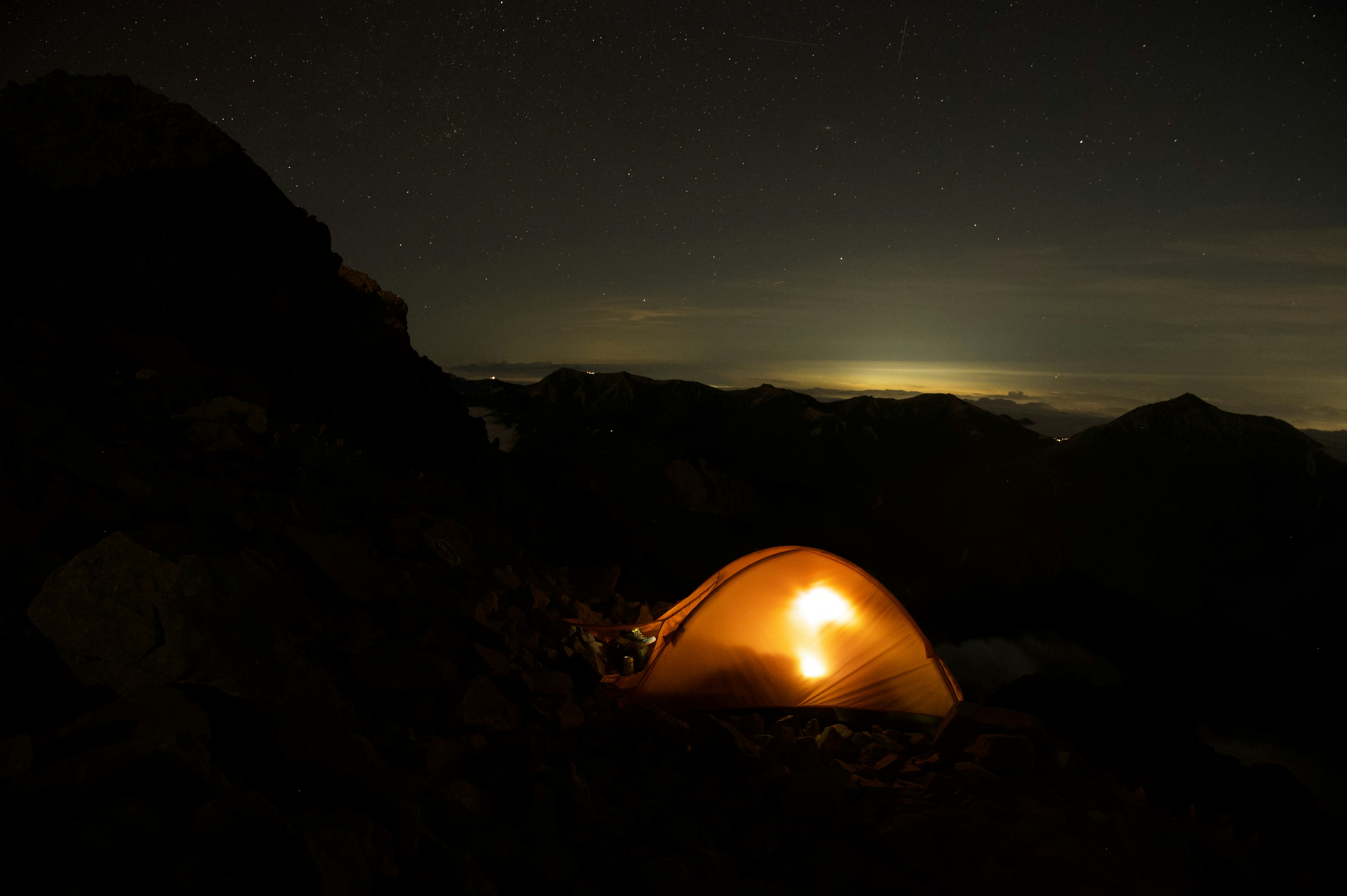 夜の山の中で光るテントが見える星空