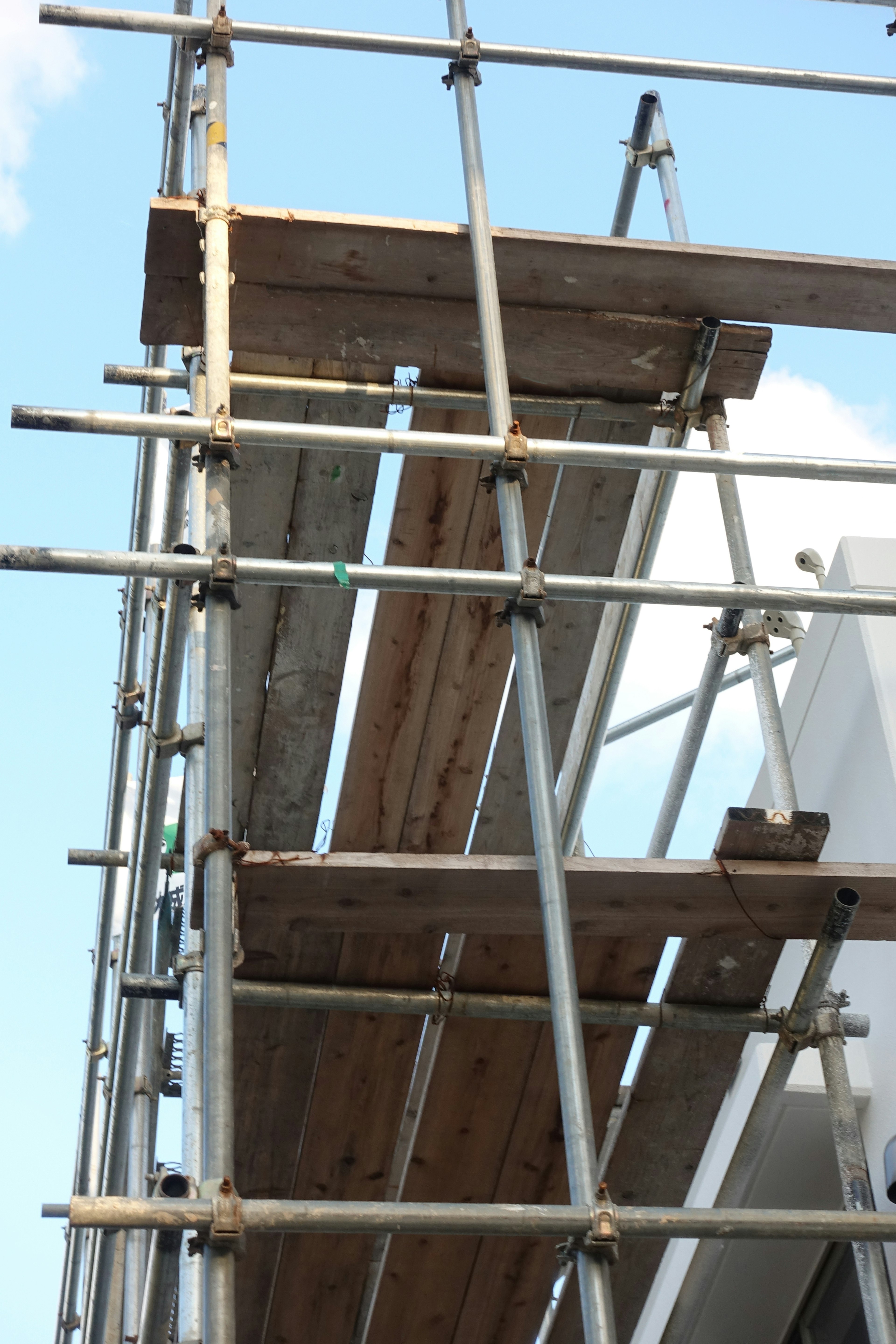 Image of a construction site featuring a metal scaffolding structure with wooden planks