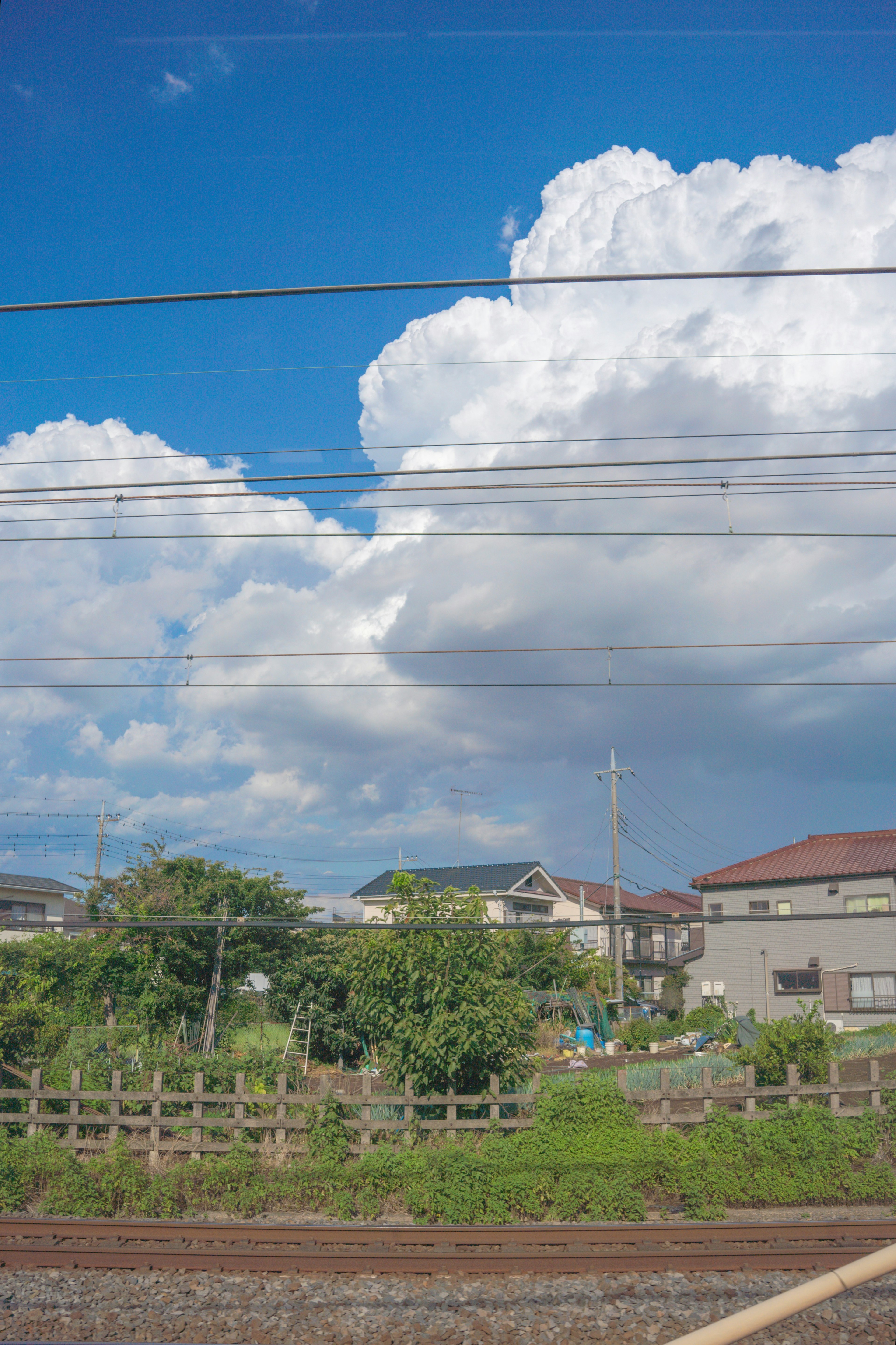 青空の下に白い雲と住宅が並ぶ風景