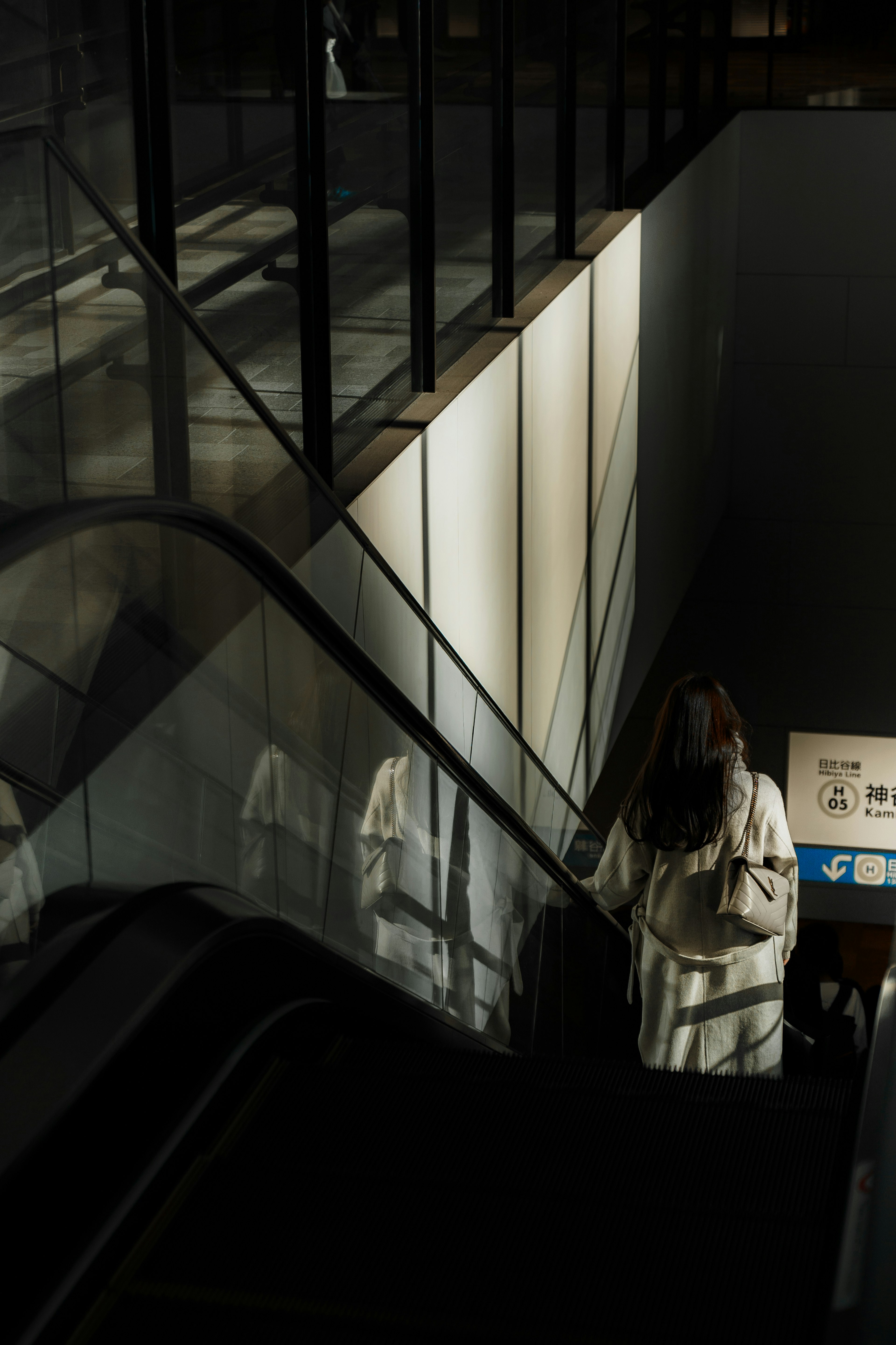 Una mujer bajando escaleras en un espacio moderno con elementos de vidrio