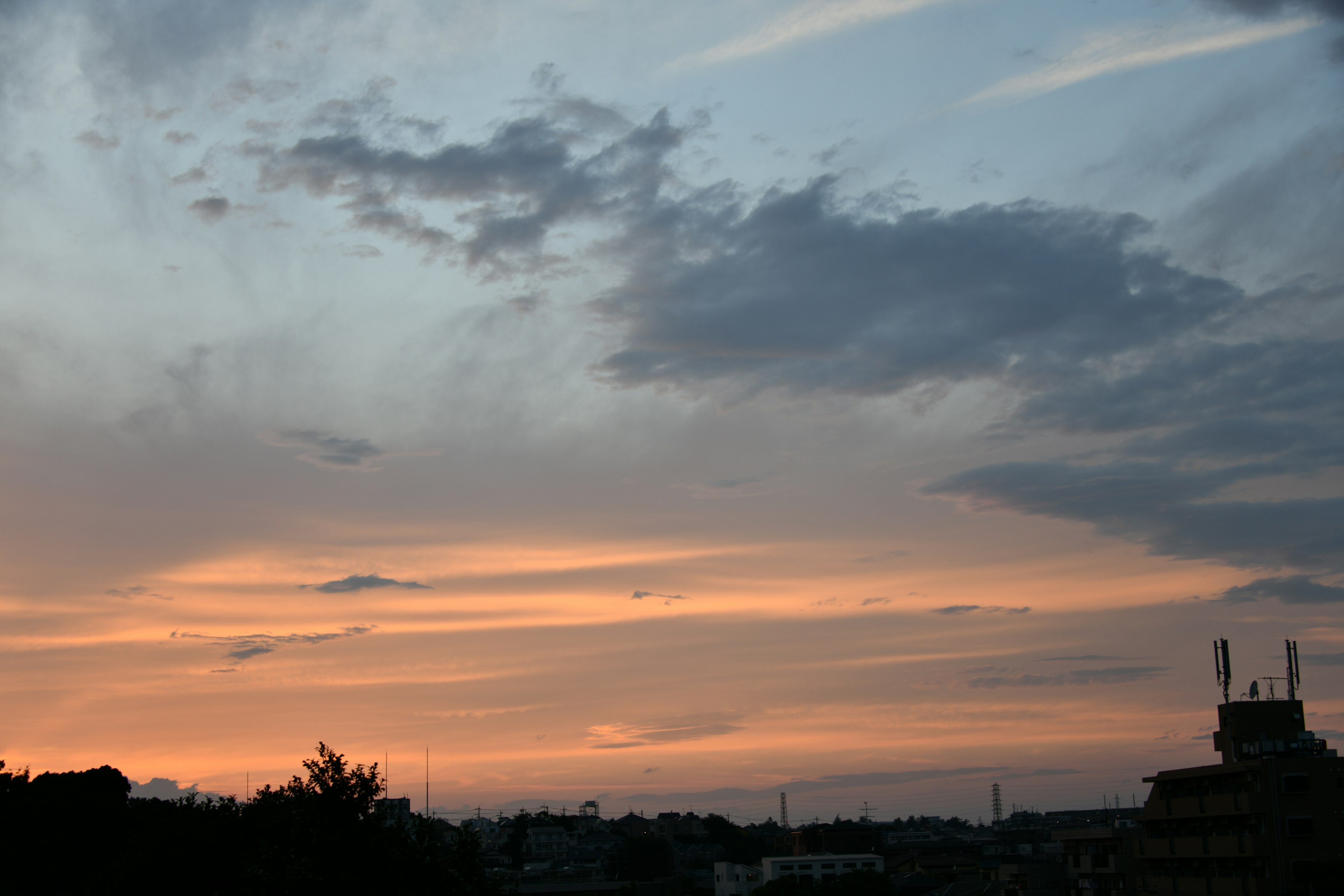 Ciel au coucher du soleil avec des nuages et des bâtiments visibles