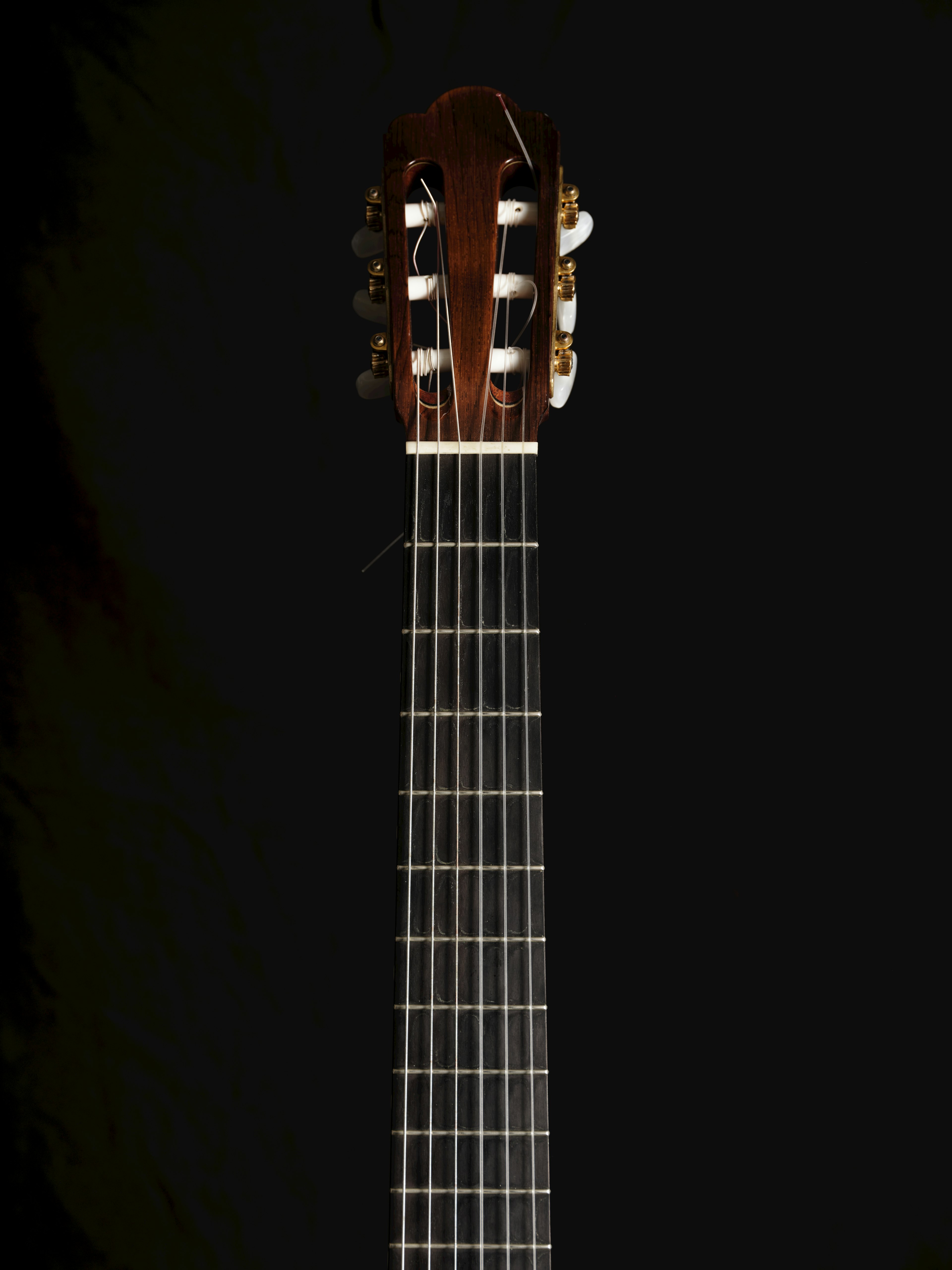 Classic guitar neck and head against a black background