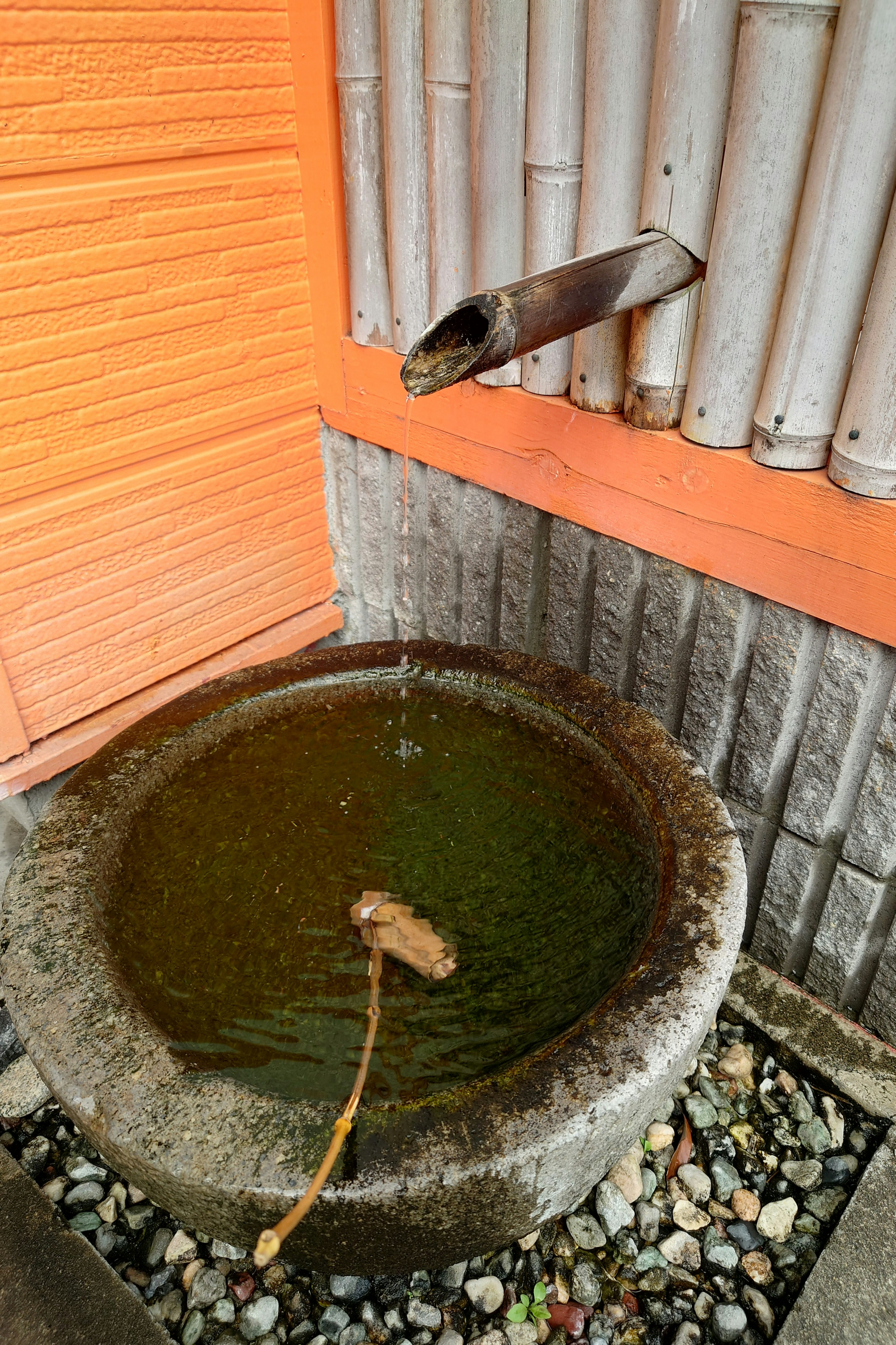 Bañera de piedra con agua fluyendo y pico de bambú