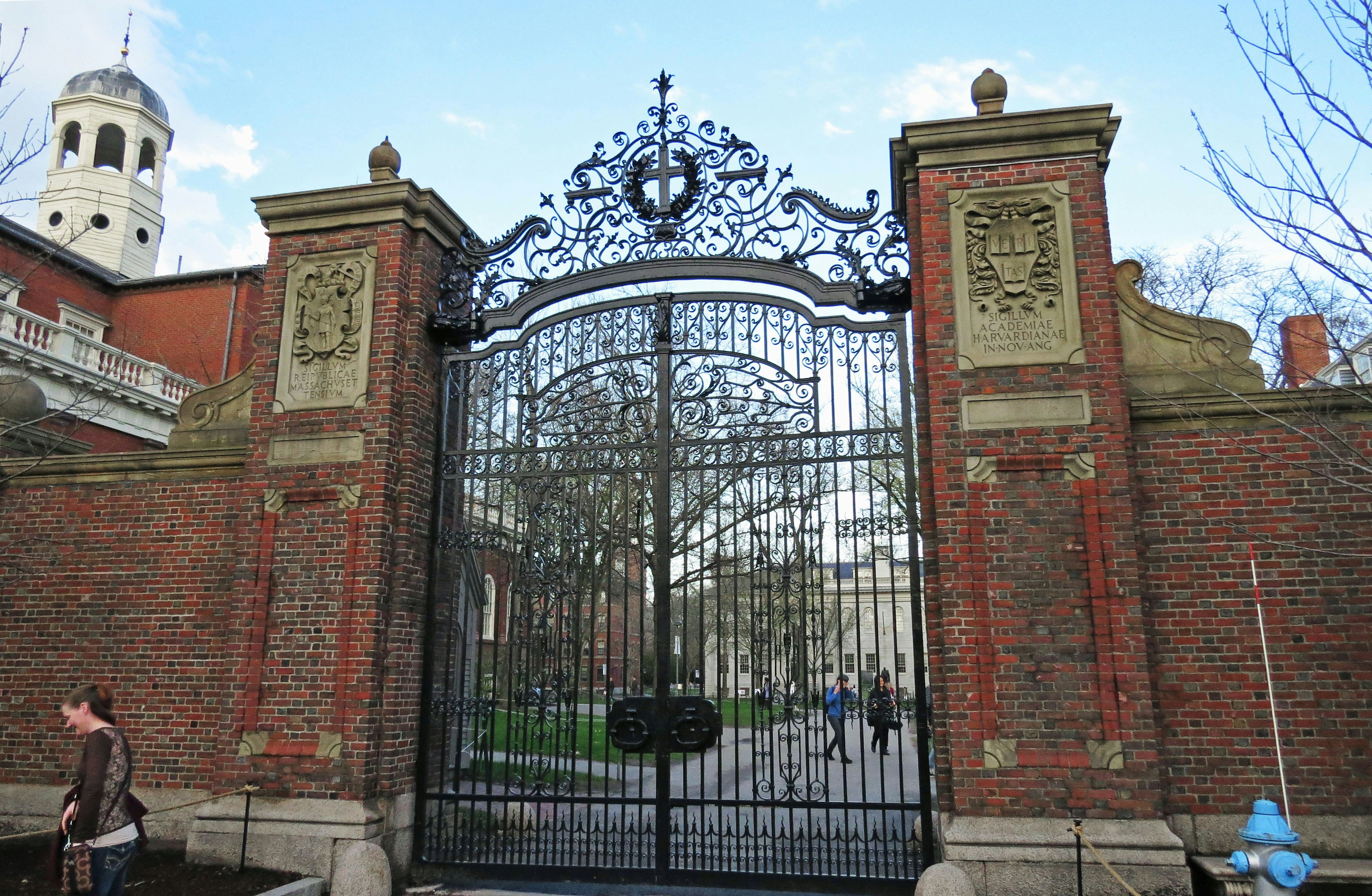 Una gran puerta de hierro ornamental con características decorativas y muros de ladrillo rojo