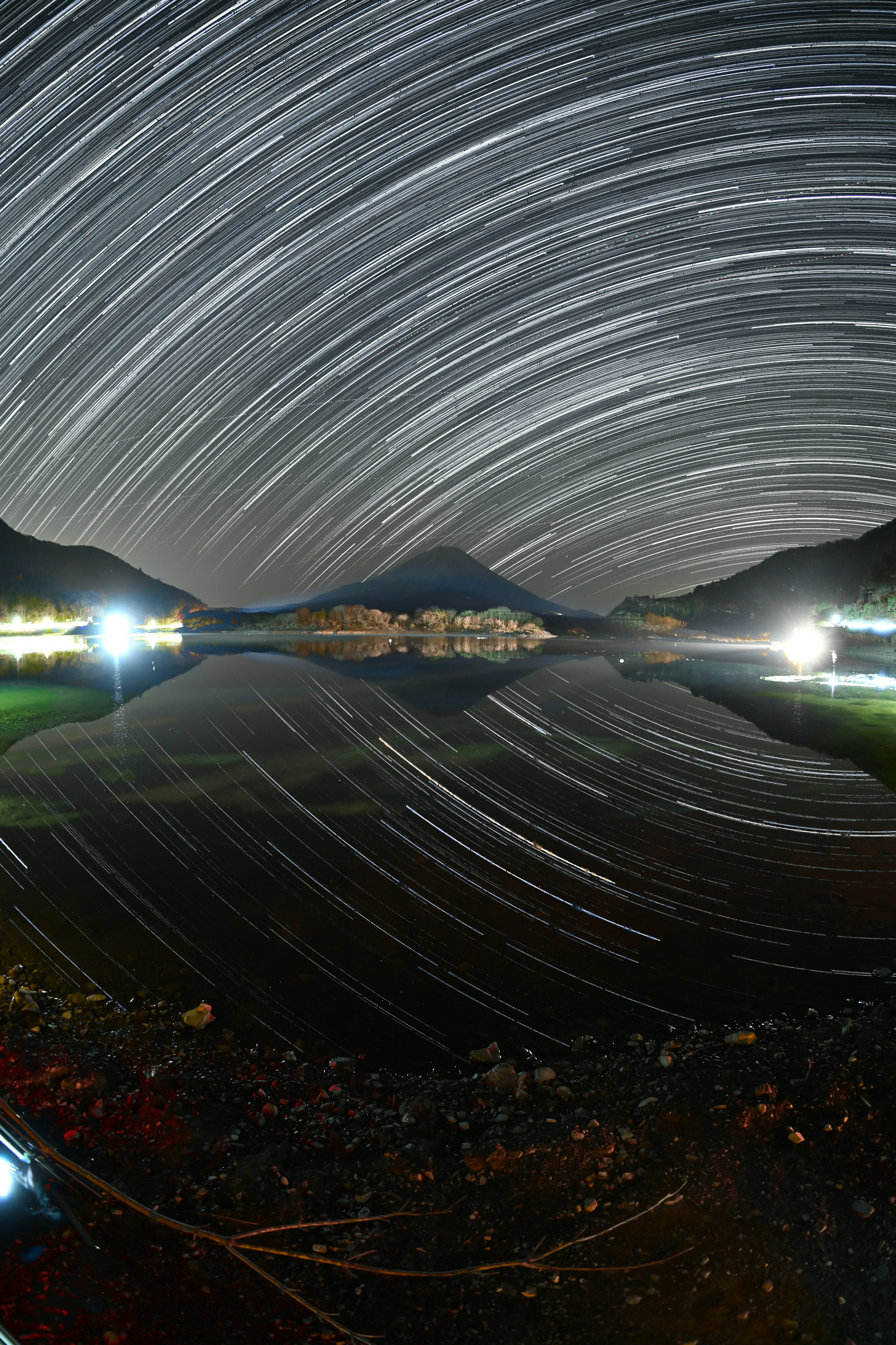 星の軌跡が映る夜空の風景 湖に反射する山と光