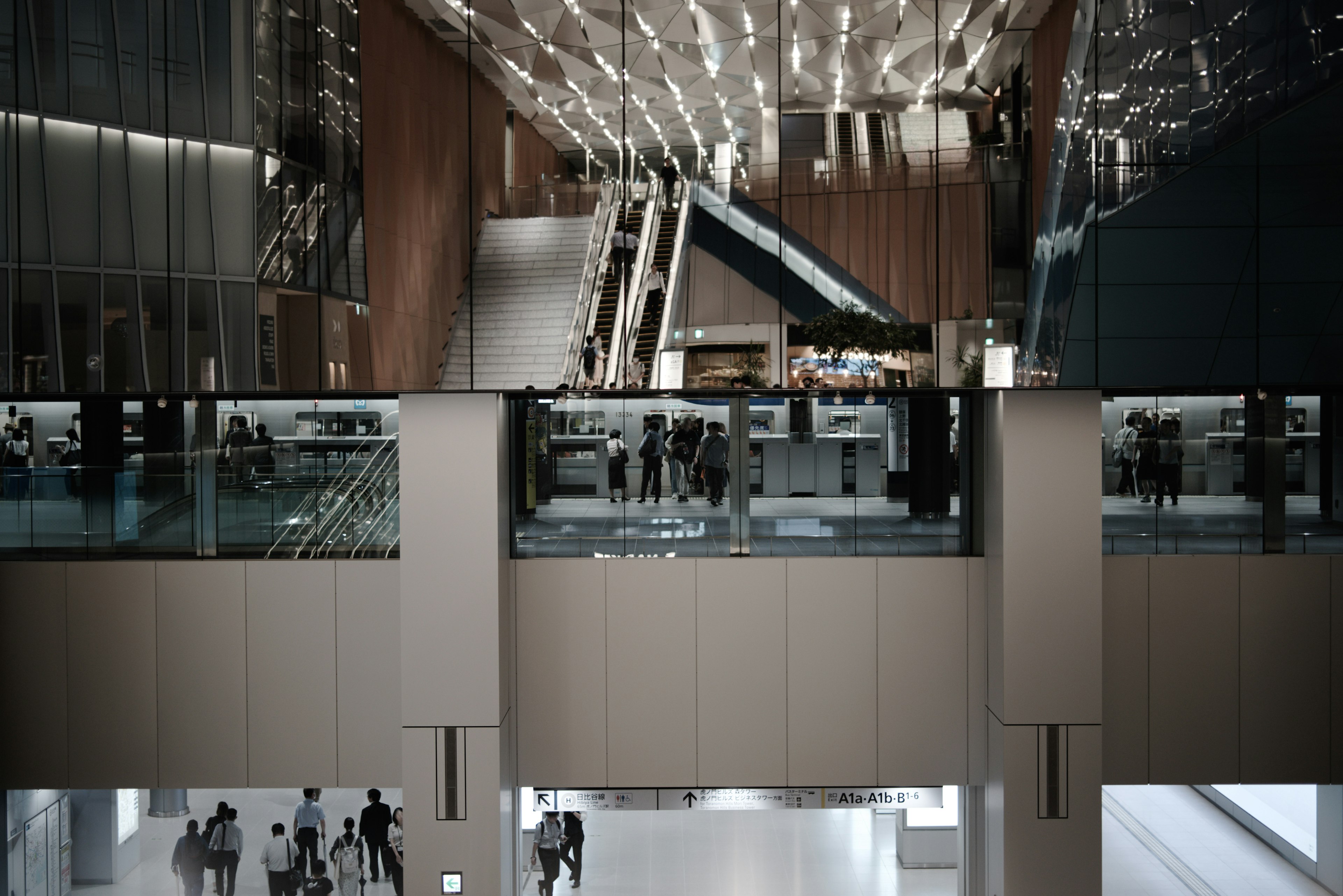 Vista interior de un edificio moderno con escaleras mecánicas y barandillas de vidrio