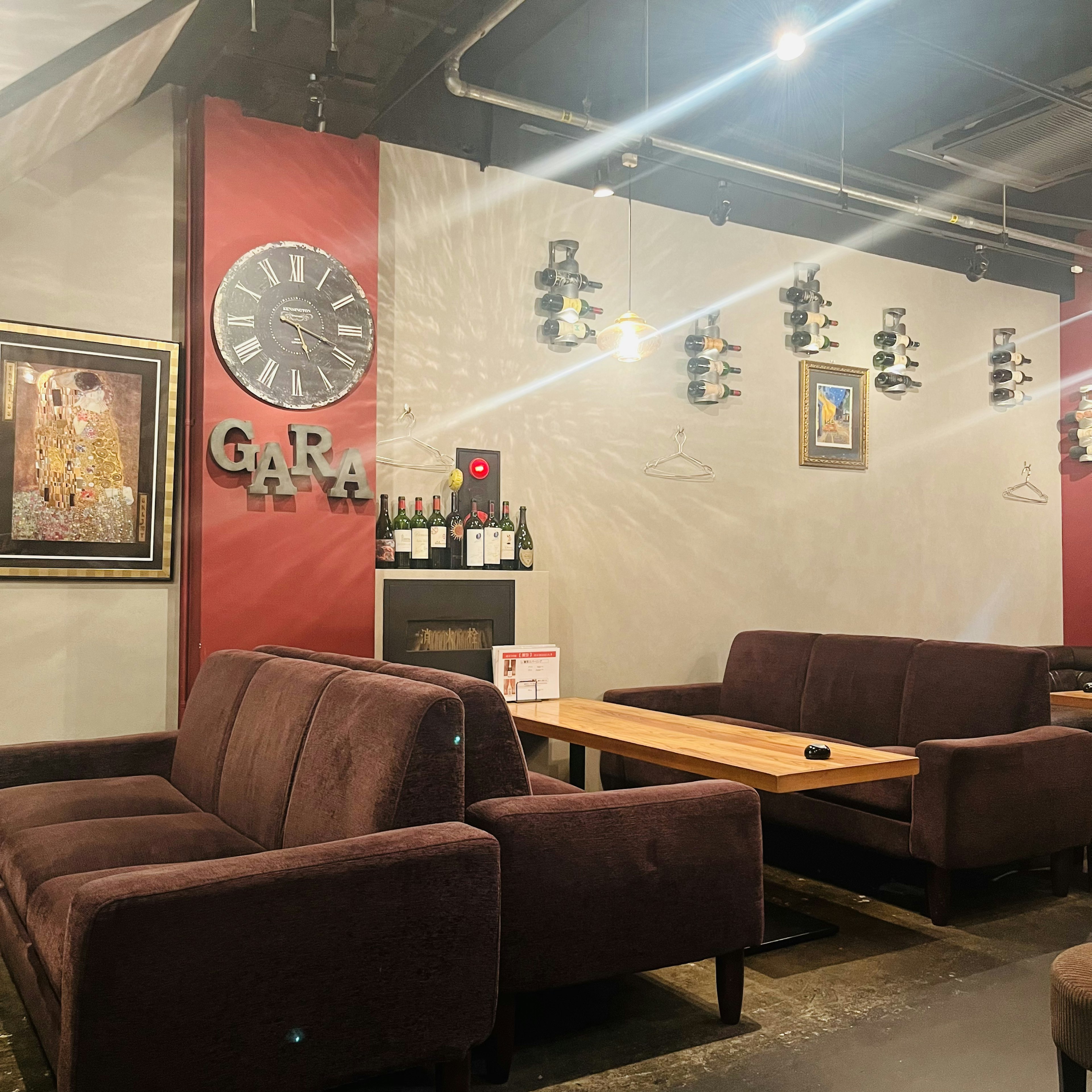 Cozy cafe interior with brown sofas and wooden tables featuring a clock and art on the wall