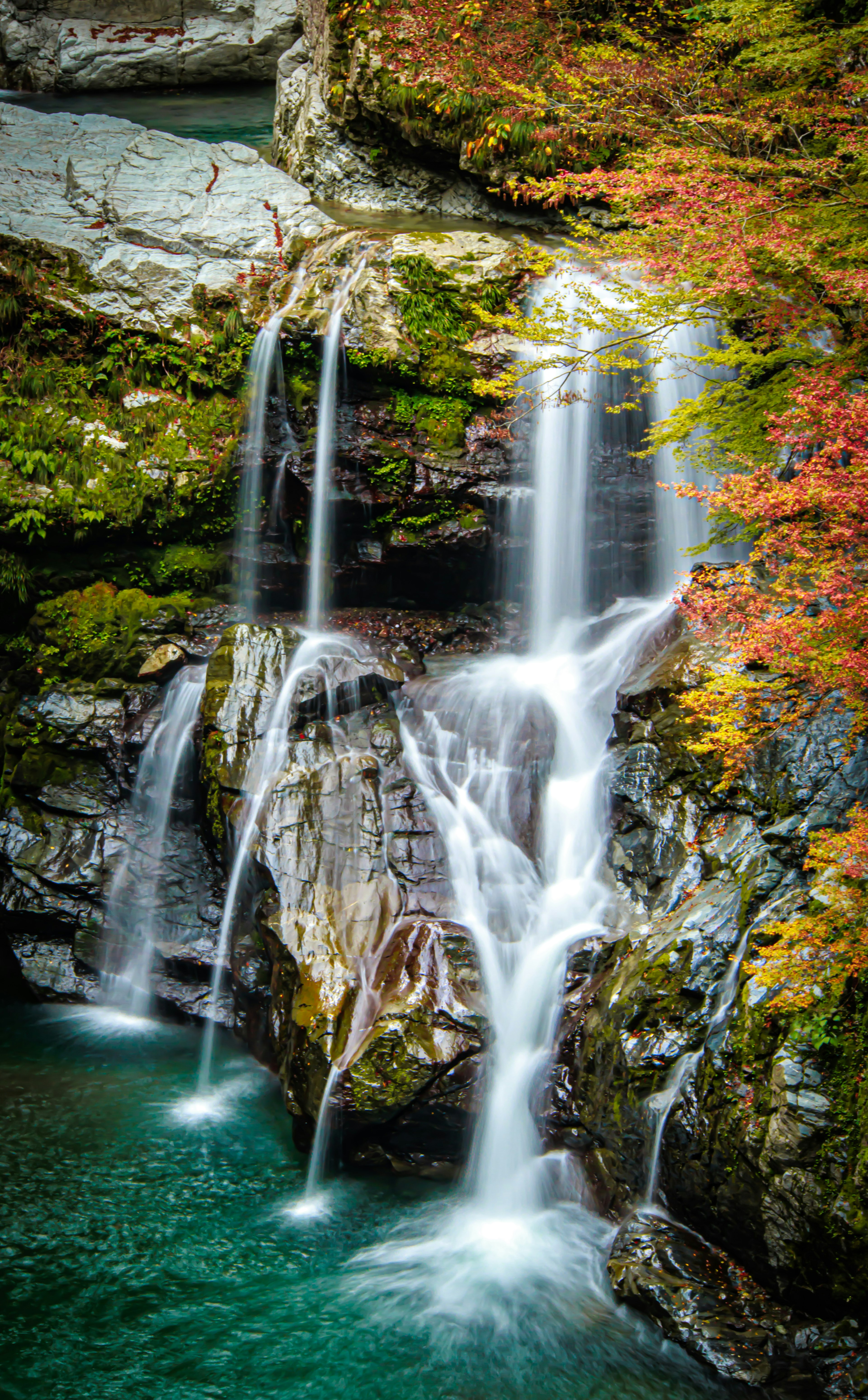 Hermosa cascada rodeada de hojas de otoño coloridas y rocas