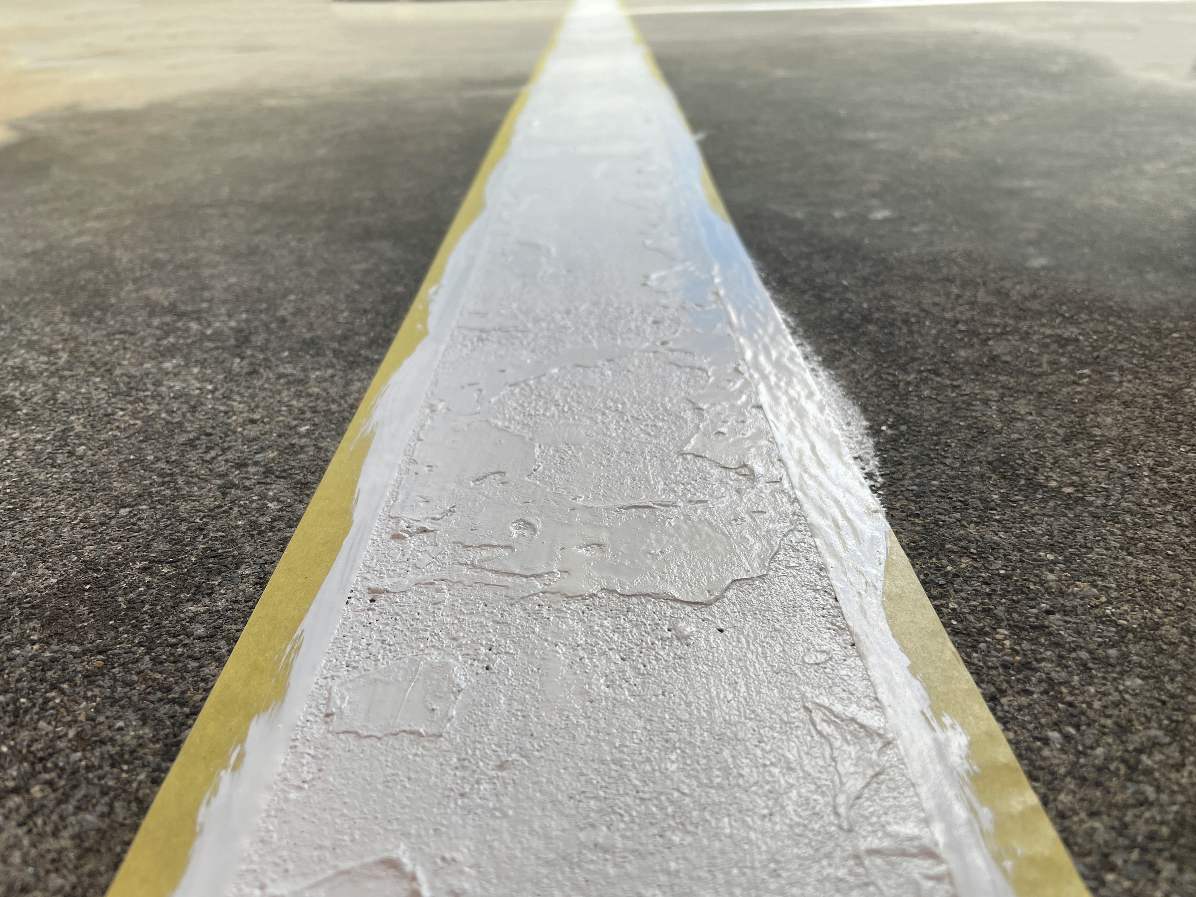 Fresh white paint applied on asphalt road surface