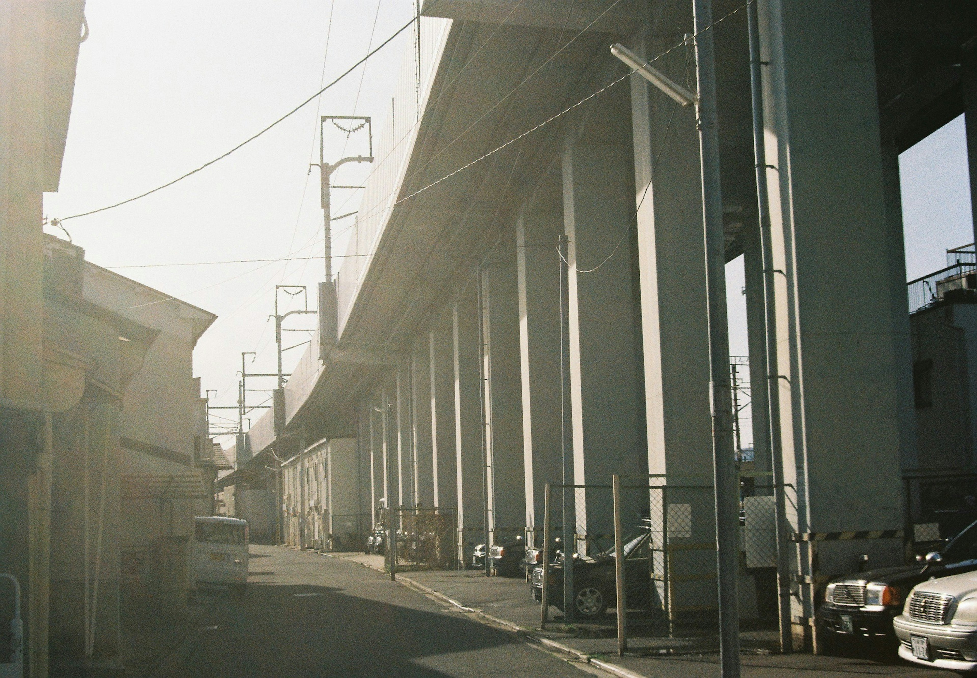 Photo of a narrow street under an elevated road