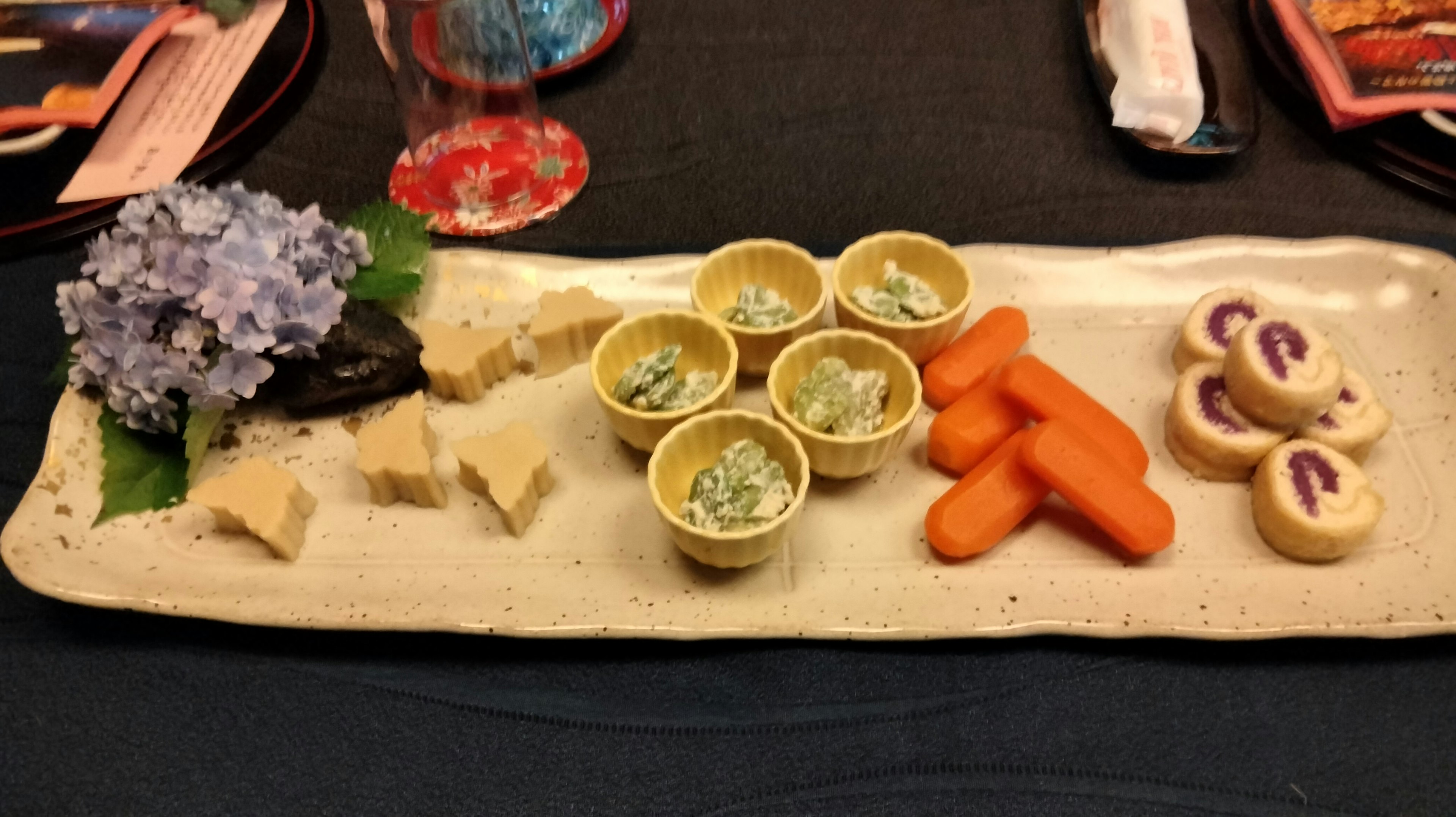 Plat japonais joliment présenté avec une fleur d'hortensia, des légumes et des desserts