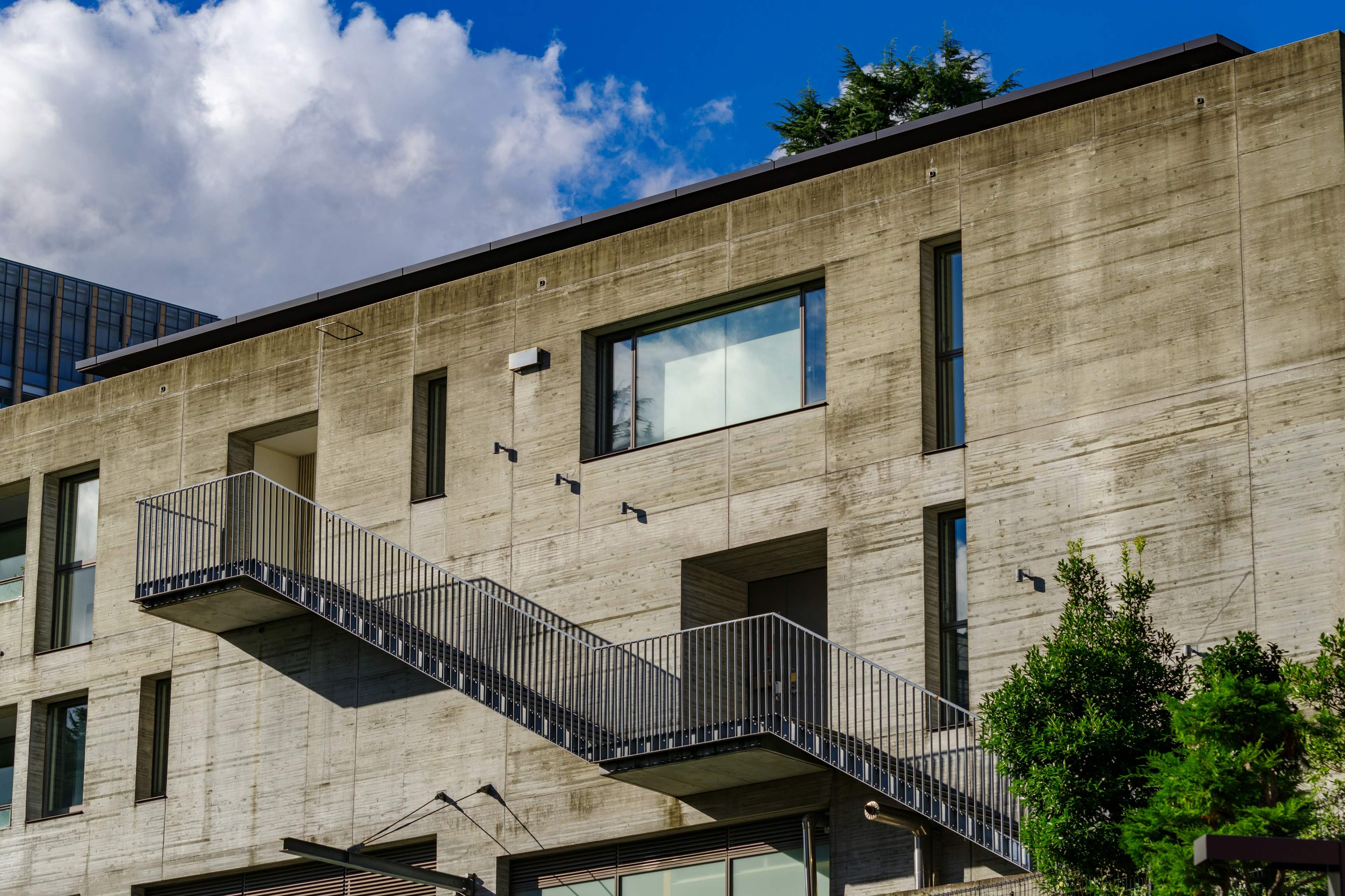 Edificio moderno con exterior de concreto que presenta una escalera y grandes ventanas