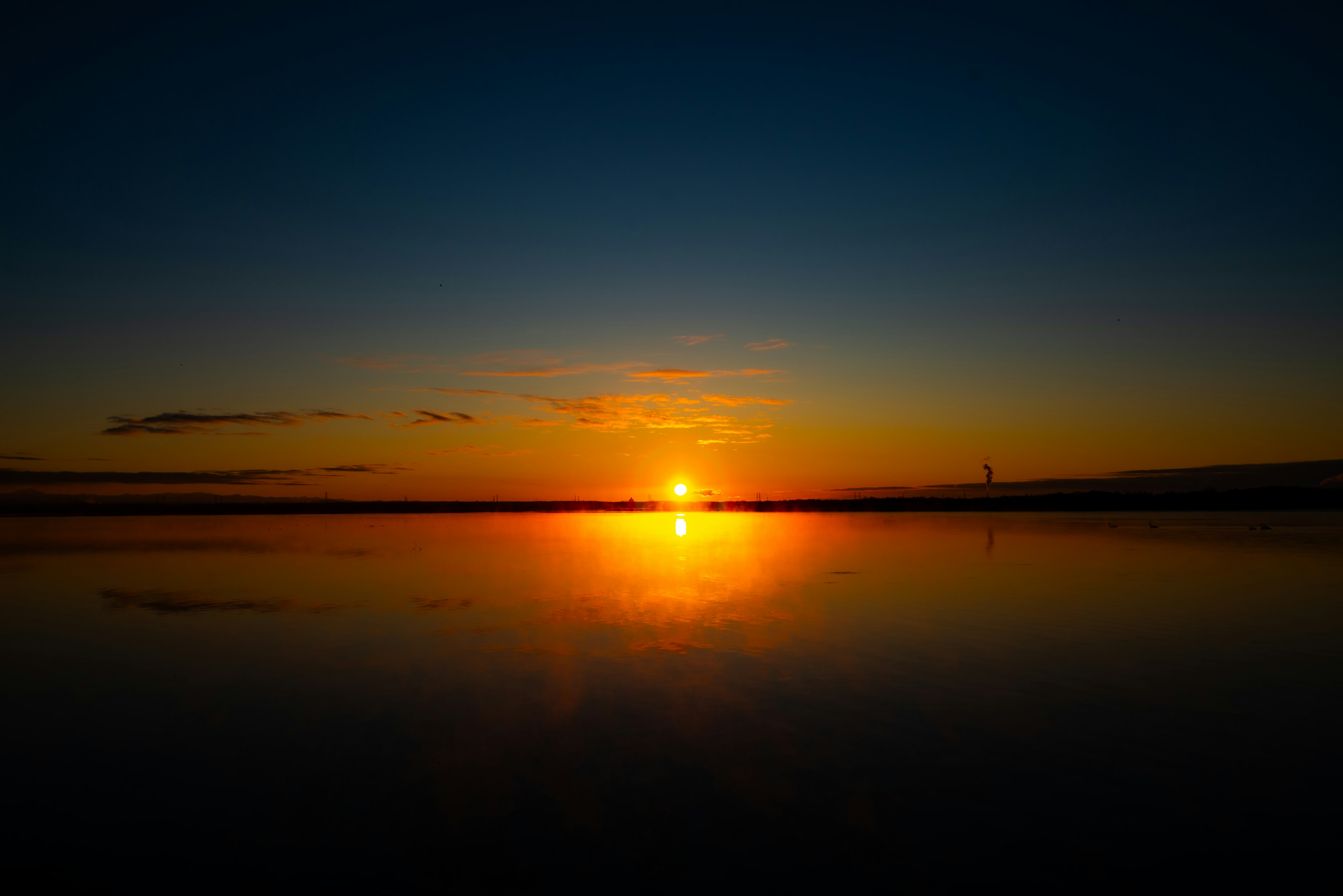 Schöner Sonnenuntergang am Horizont mit orangefarbenen Reflexionen auf dem Wasser