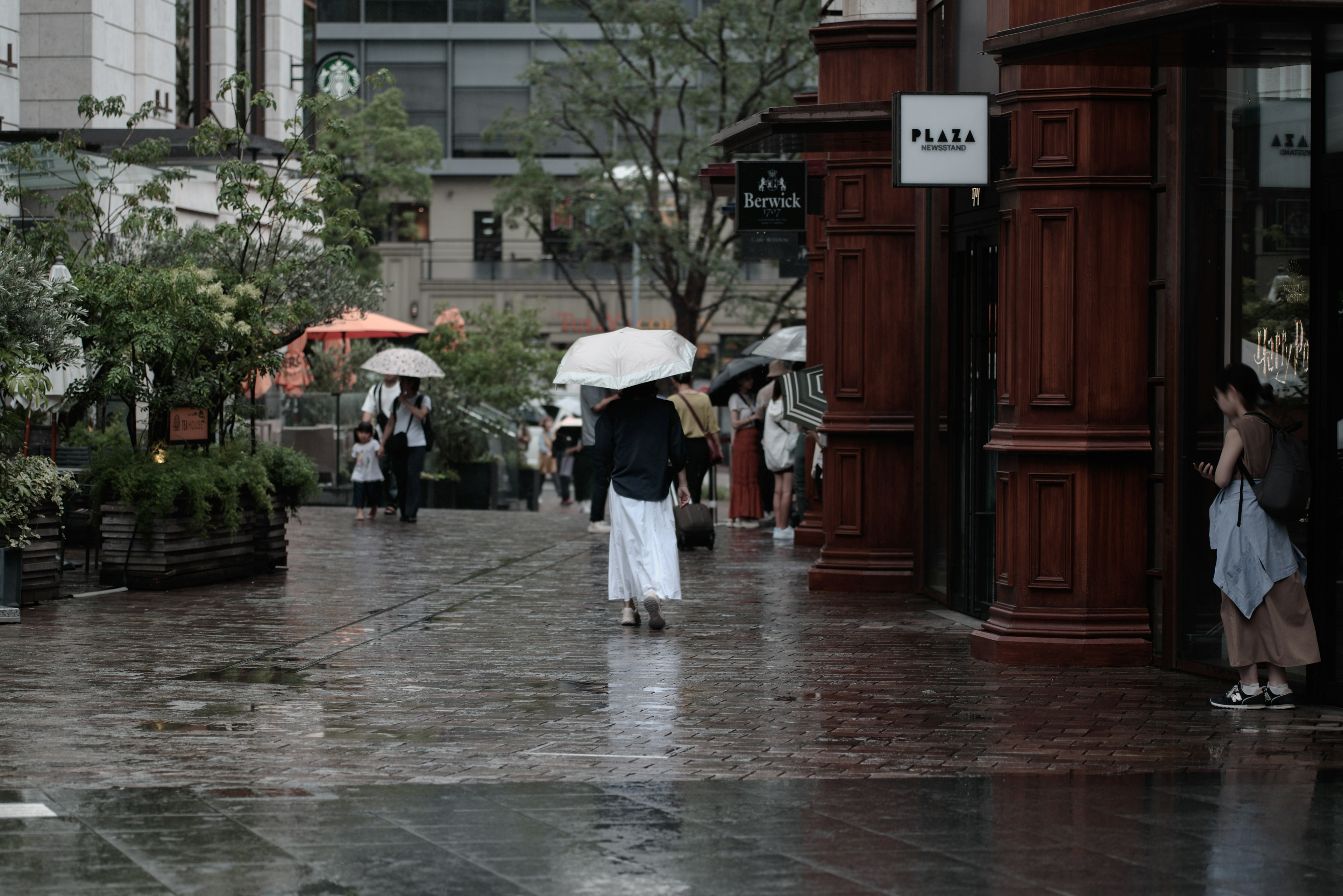 Scène de ville avec des personnes marchant sous des parapluies sous la pluie