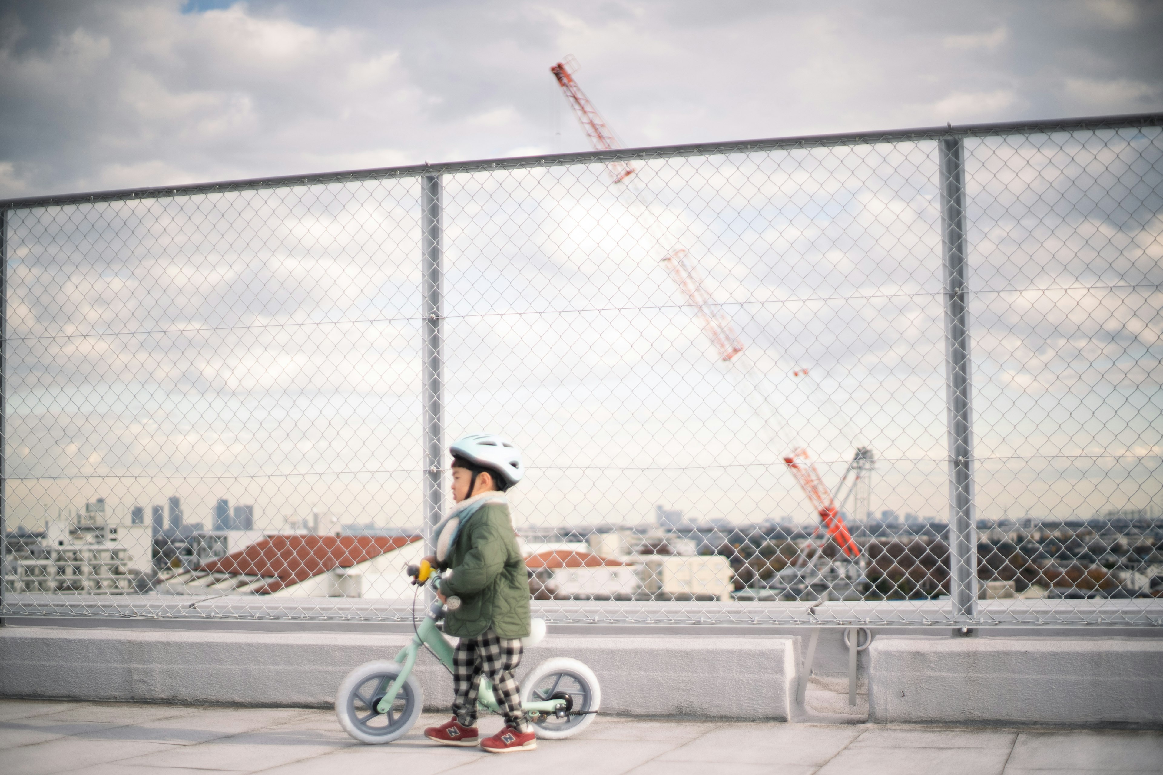 屋上で自転車に乗る子供と背景のクレーン