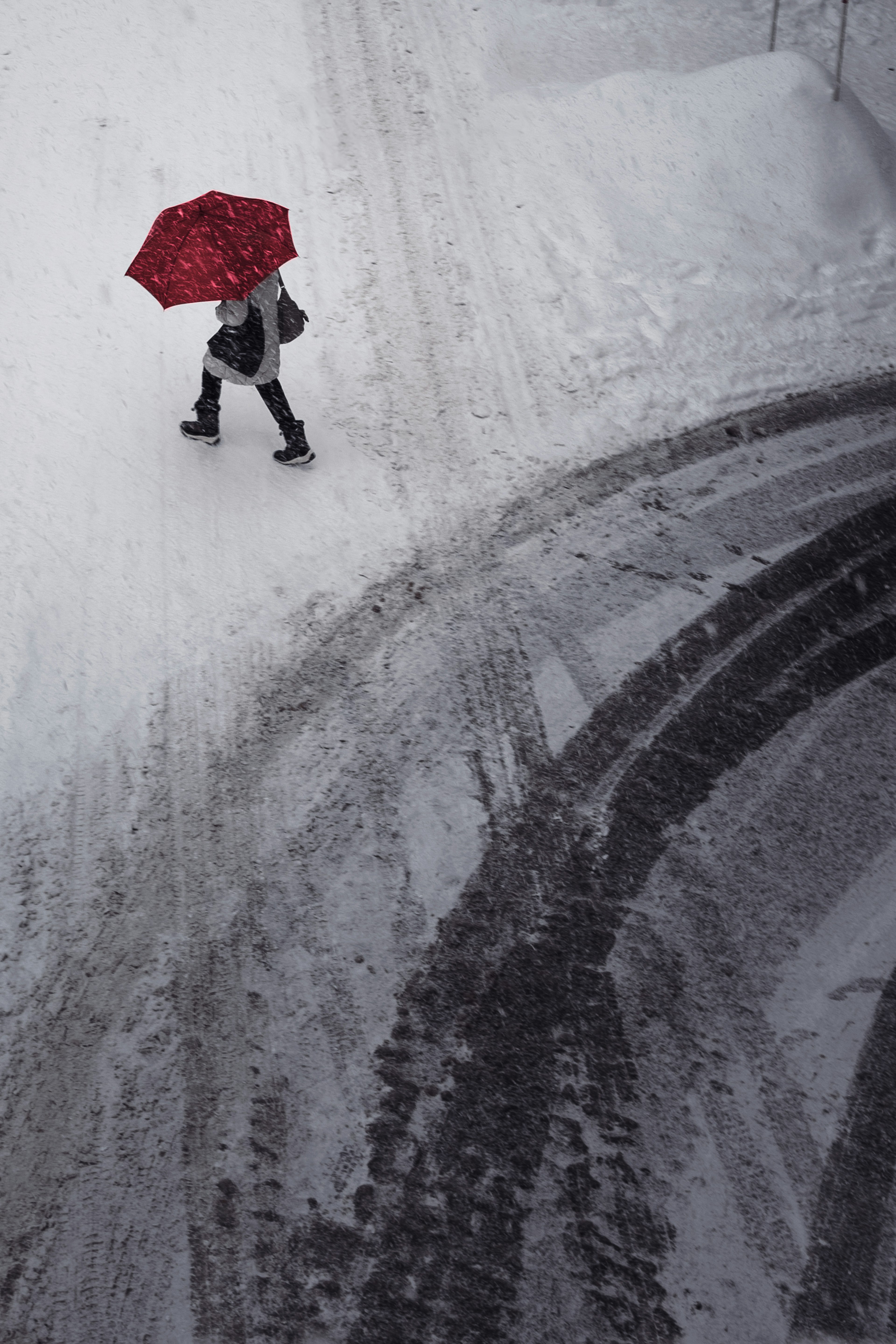 Person walking in the snow with a red umbrella