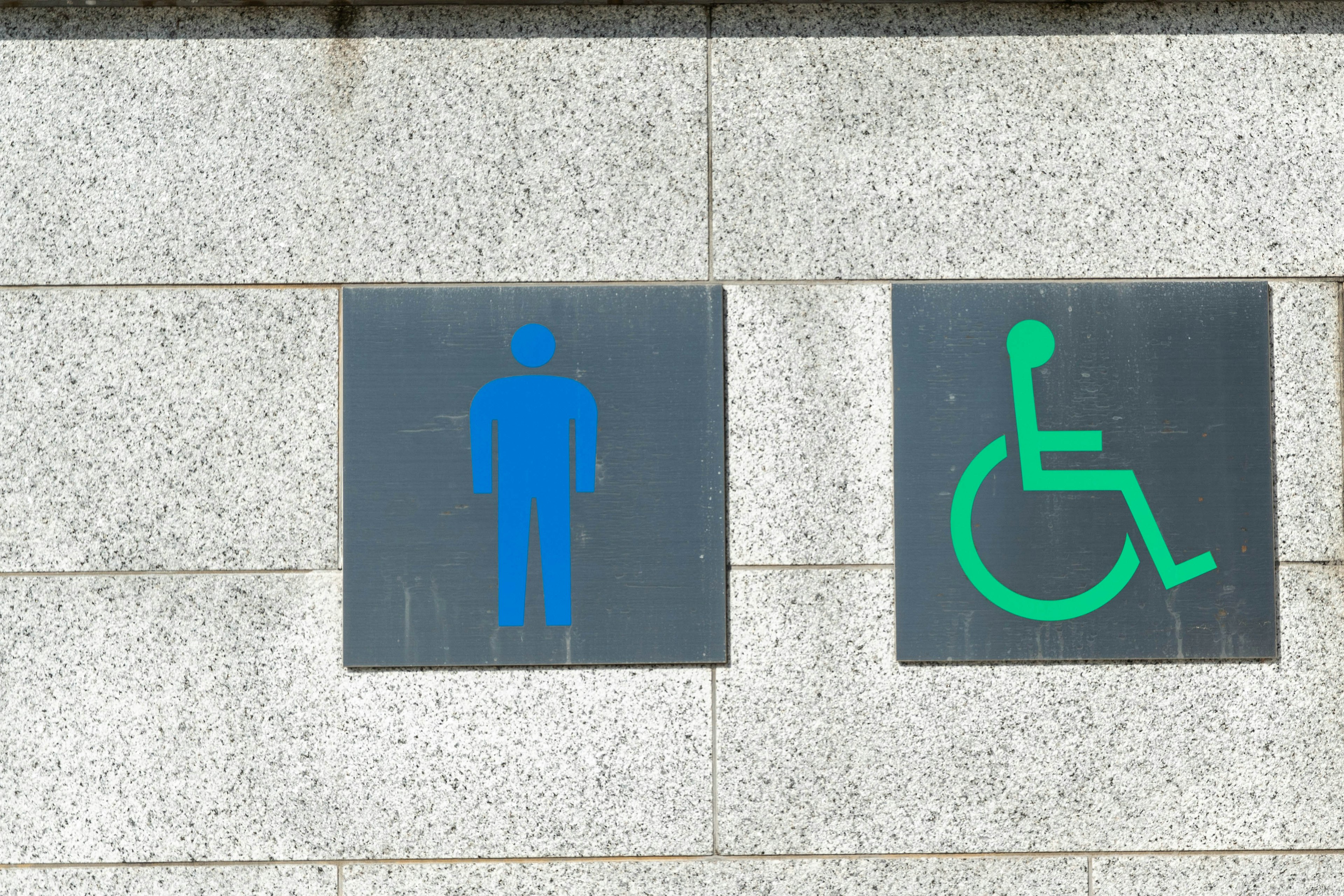 Señal azul de baño para hombres y señal verde de baño accesible en una pared