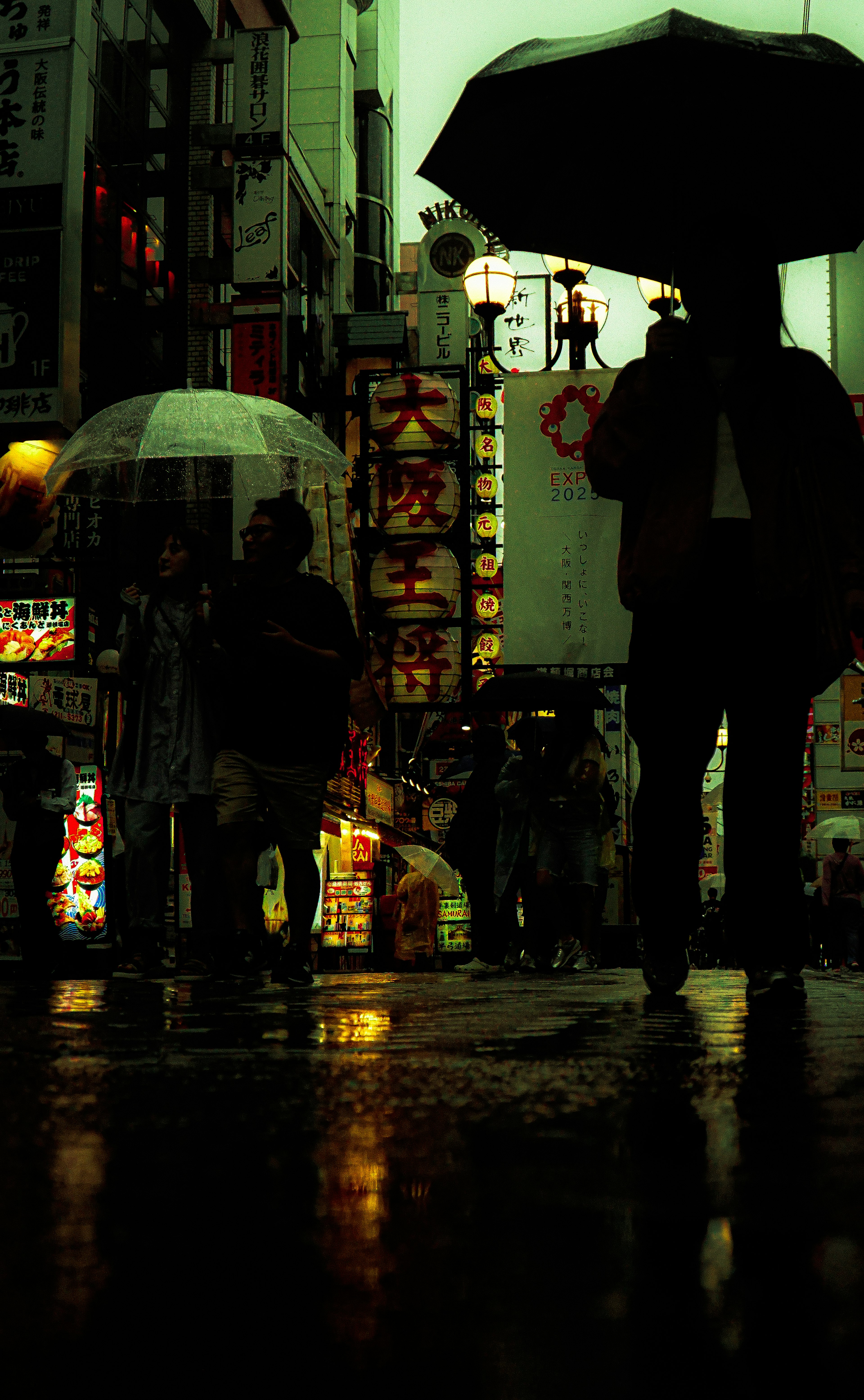 雨の中のシルエットとネオンの看板が映る都市の風景