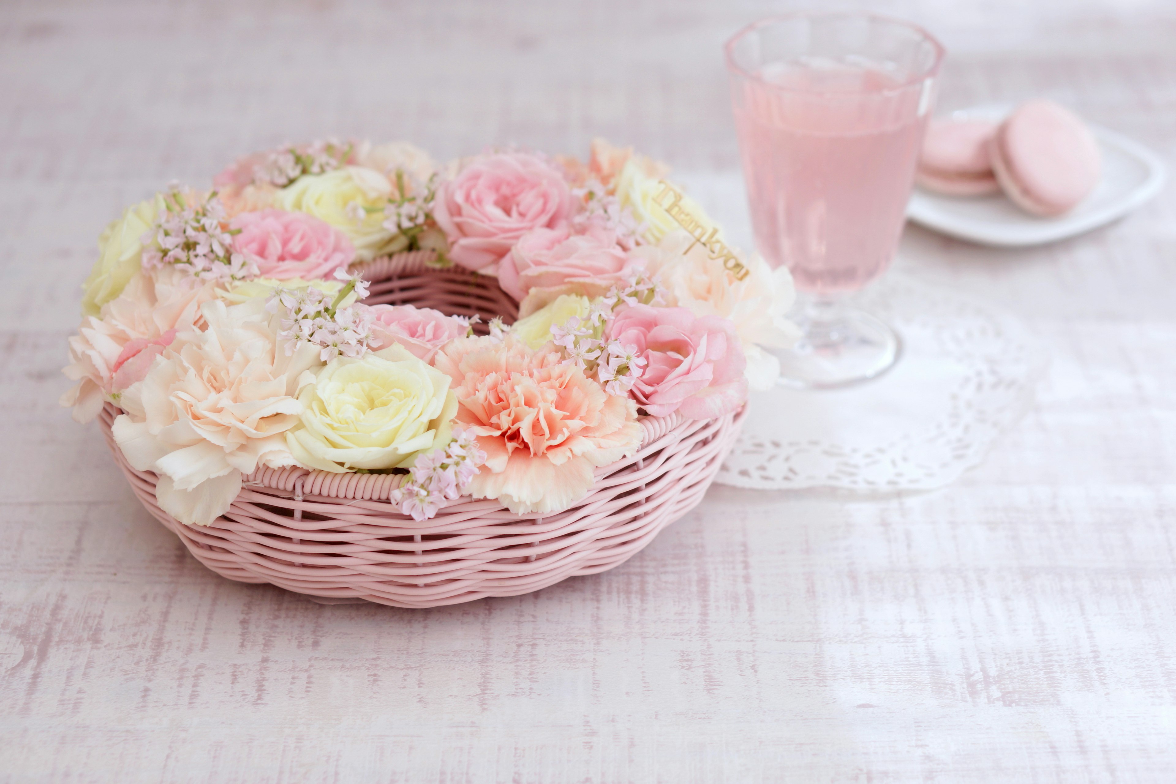 Una cesta adornada con flores rosas y una bebida rosa claro