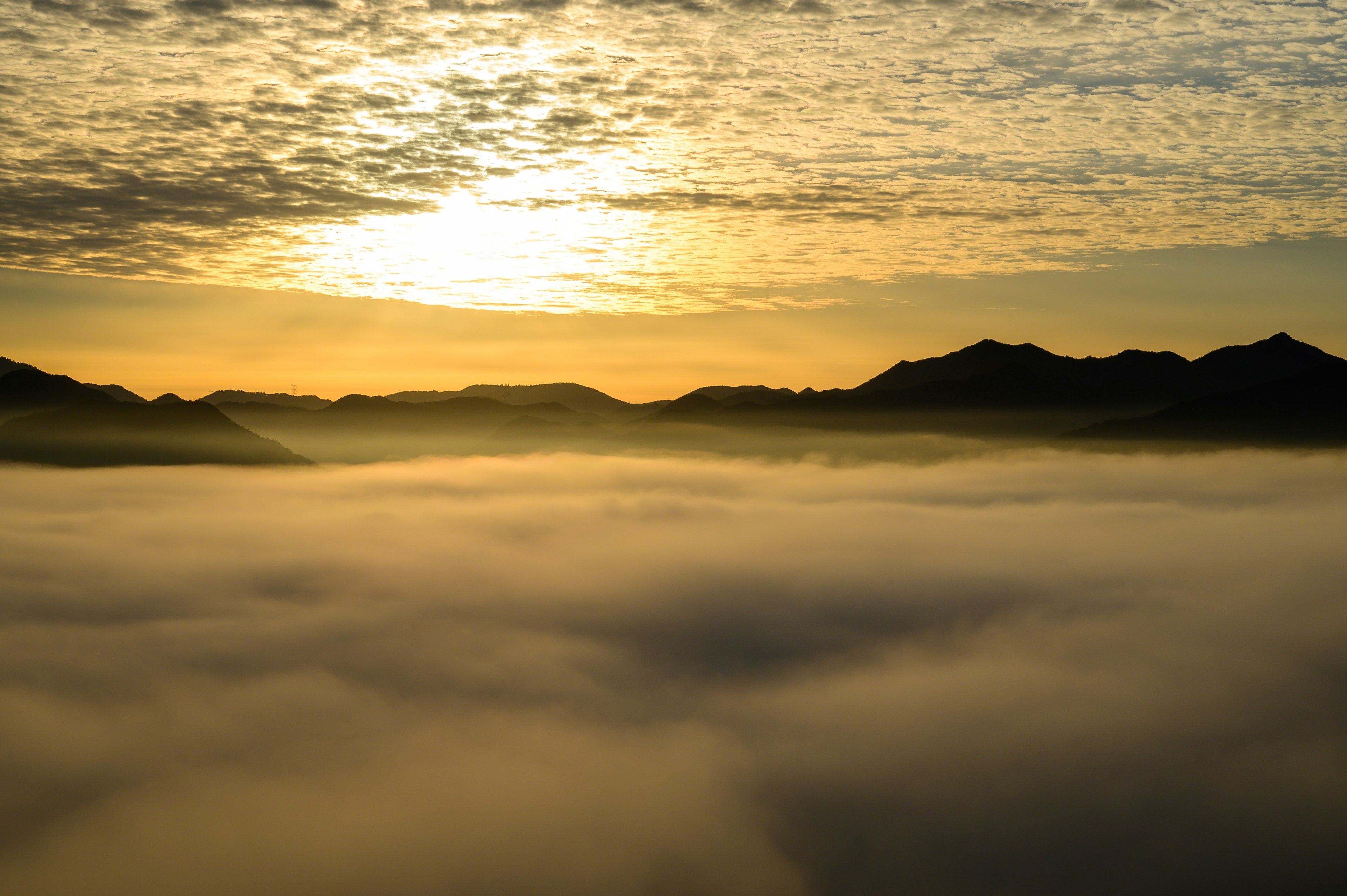 霧に包まれた山々と夕日が美しい風景