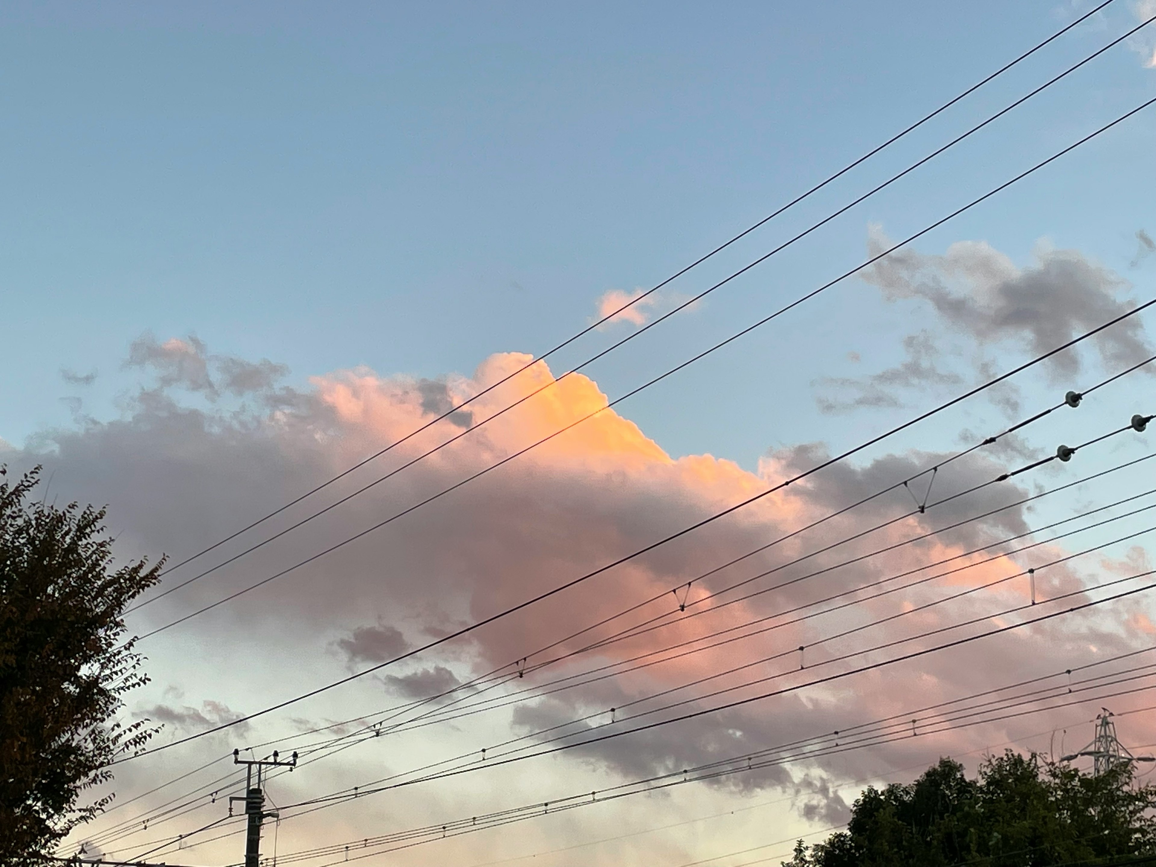 Nubes iluminadas por el atardecer con líneas eléctricas