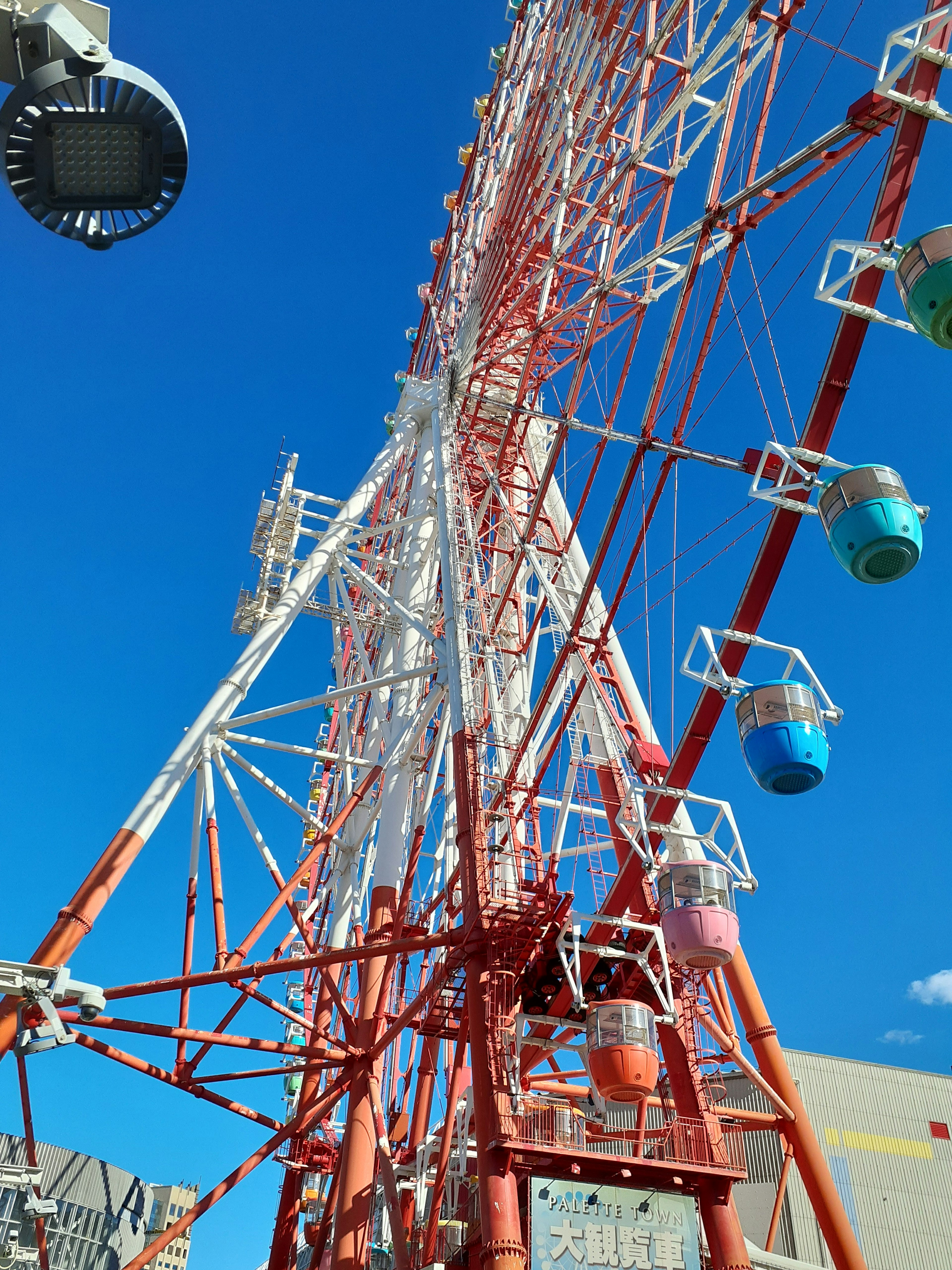 Ferris wheel đầy màu sắc với cấu trúc đỏ và bầu trời xanh phía sau