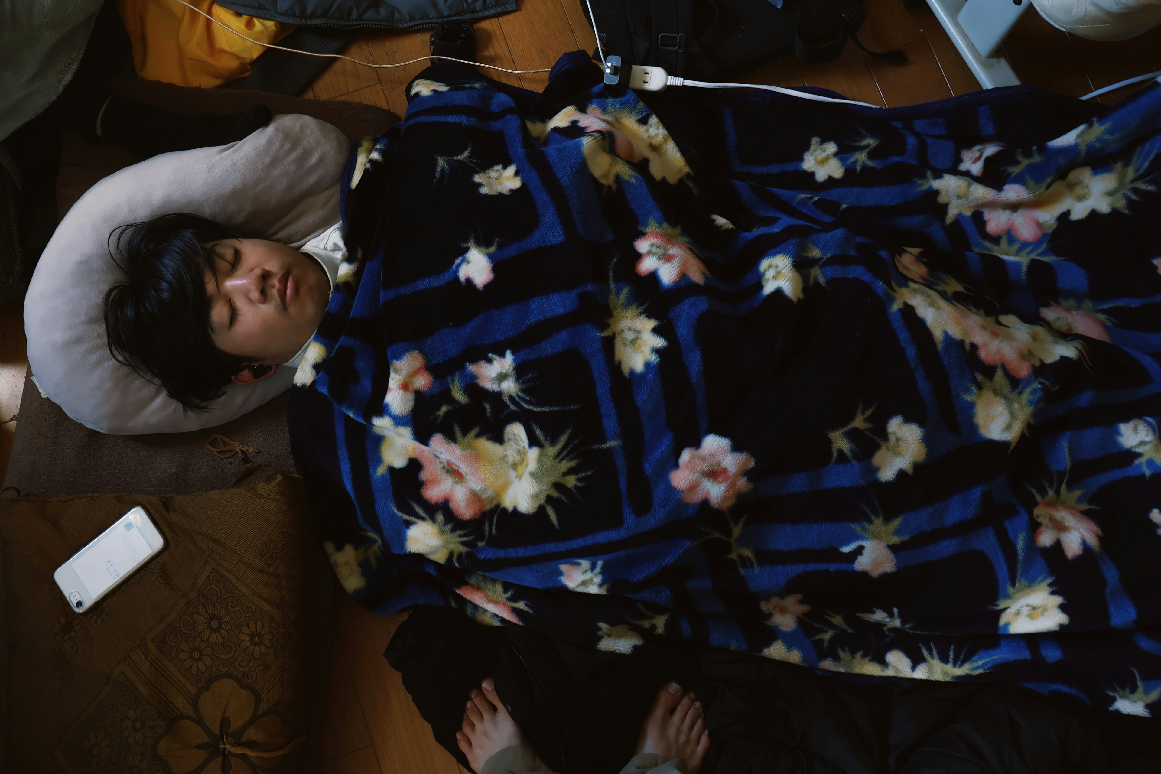 Young man sleeping on a couch covered with a floral blanket