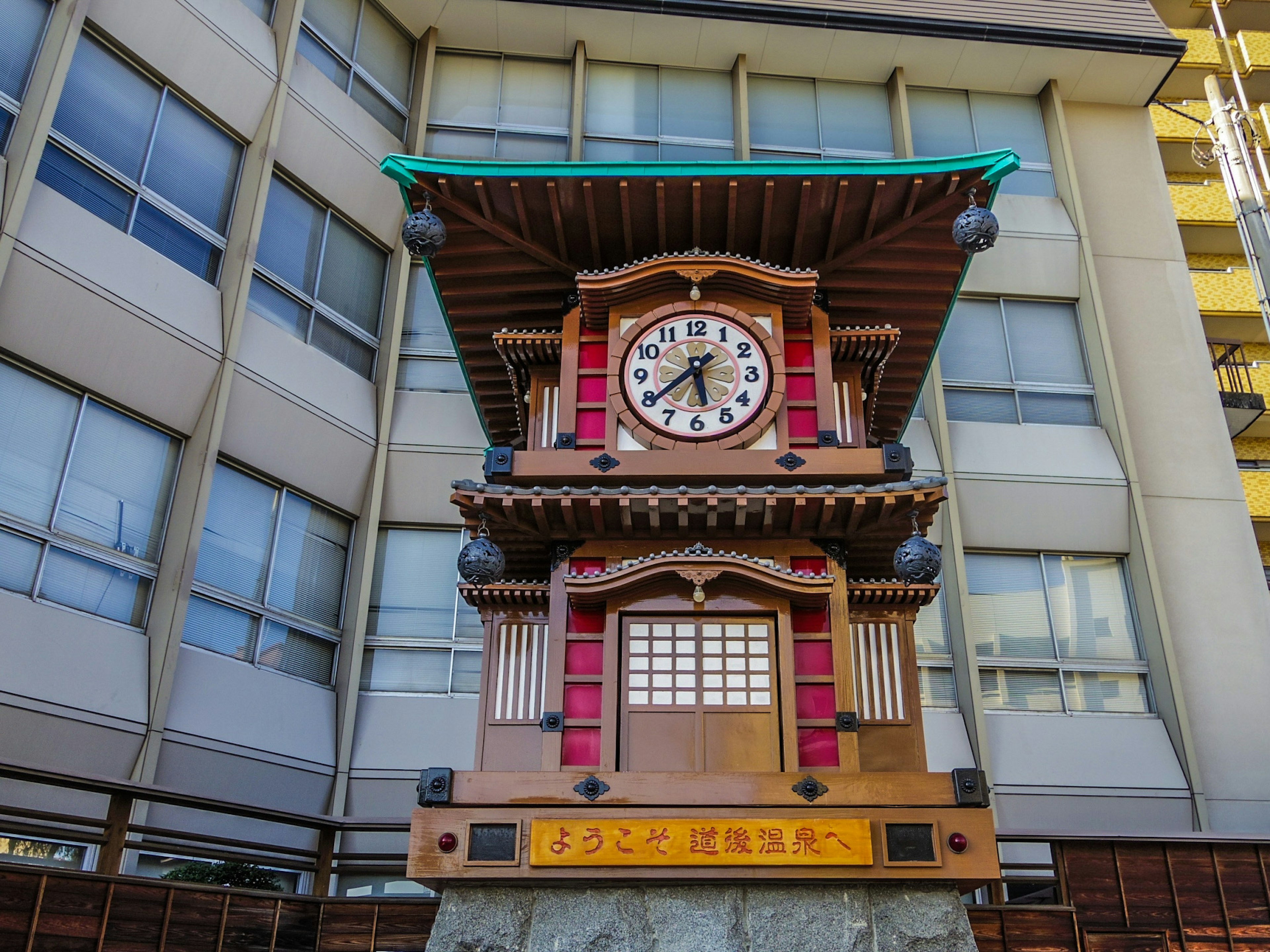 Torre del reloj japonesa tradicional frente a un edificio moderno