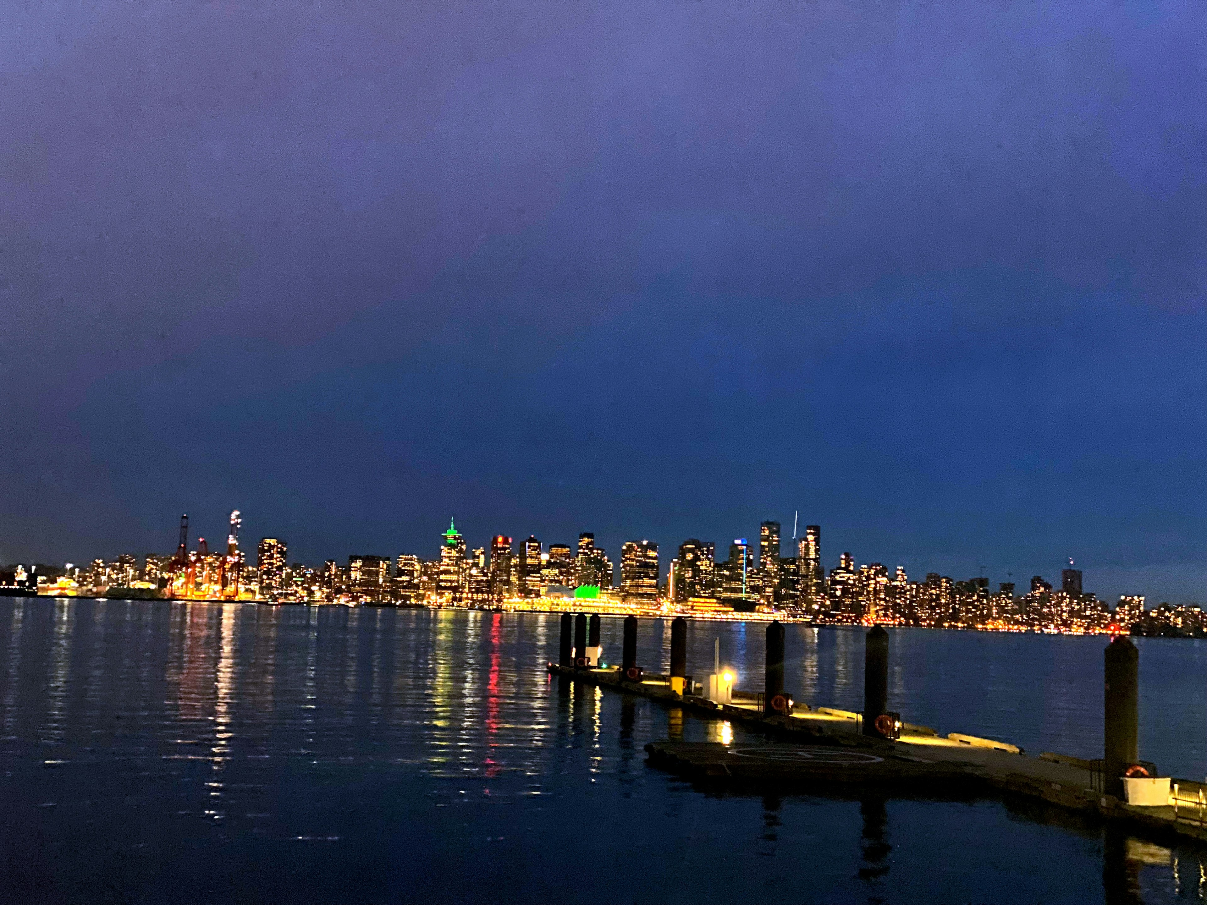 Skyline di Seattle di notte con riflessi sull'acqua e un molo