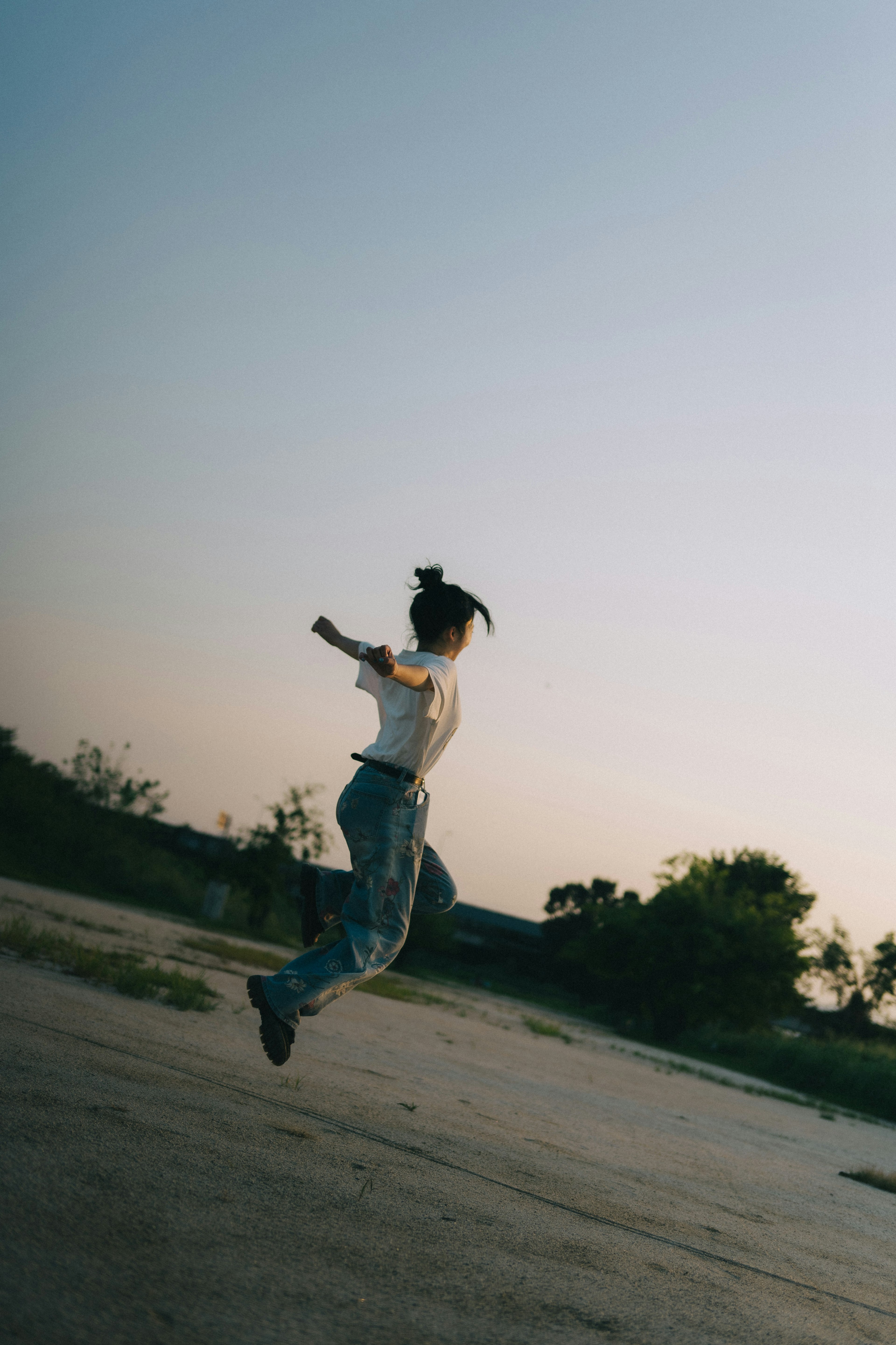 Silhouette of a woman jumping at sunset with natural landscape in the background