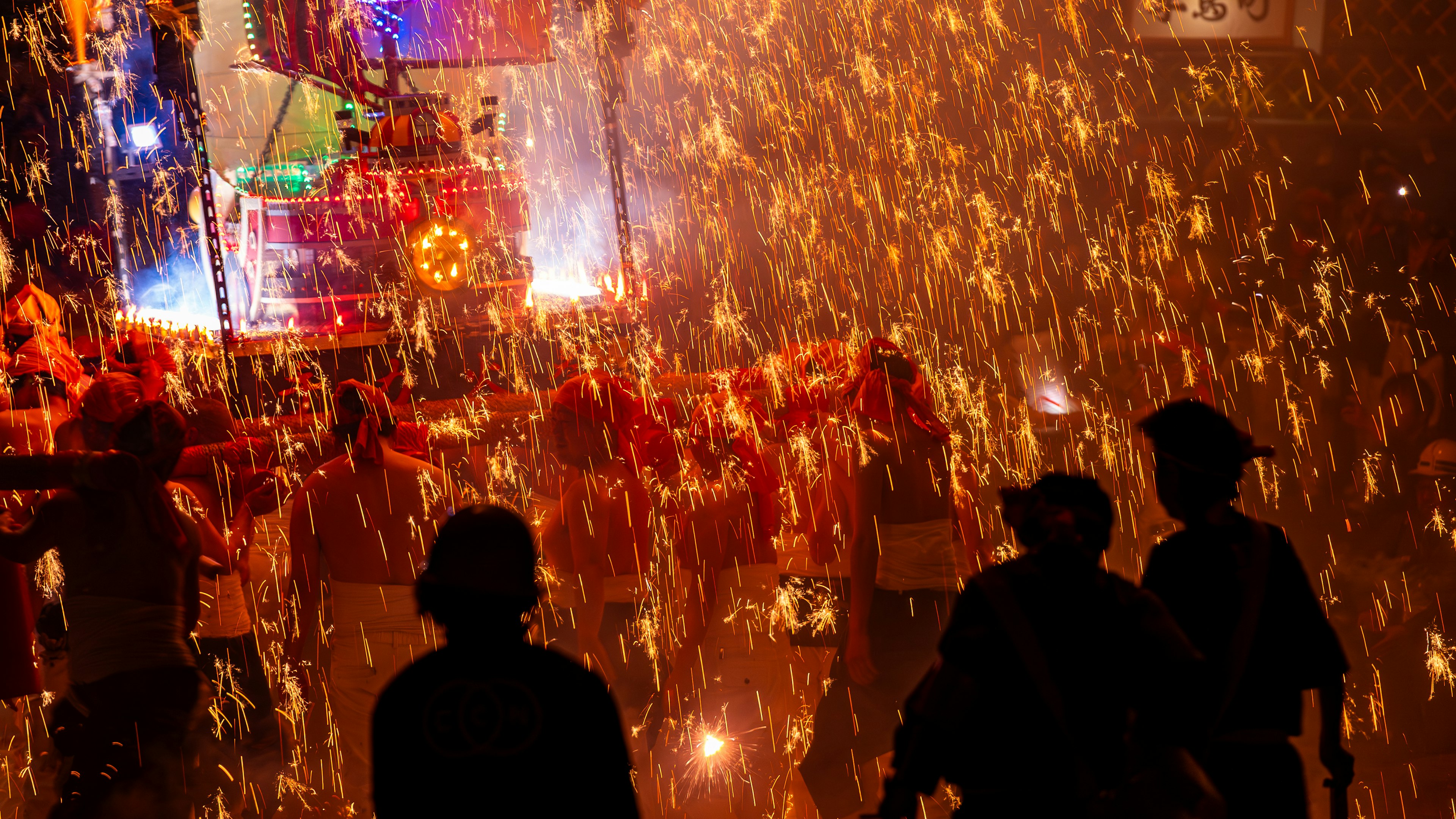 火花が飛び散る祭りの光景人々が周囲に立っている