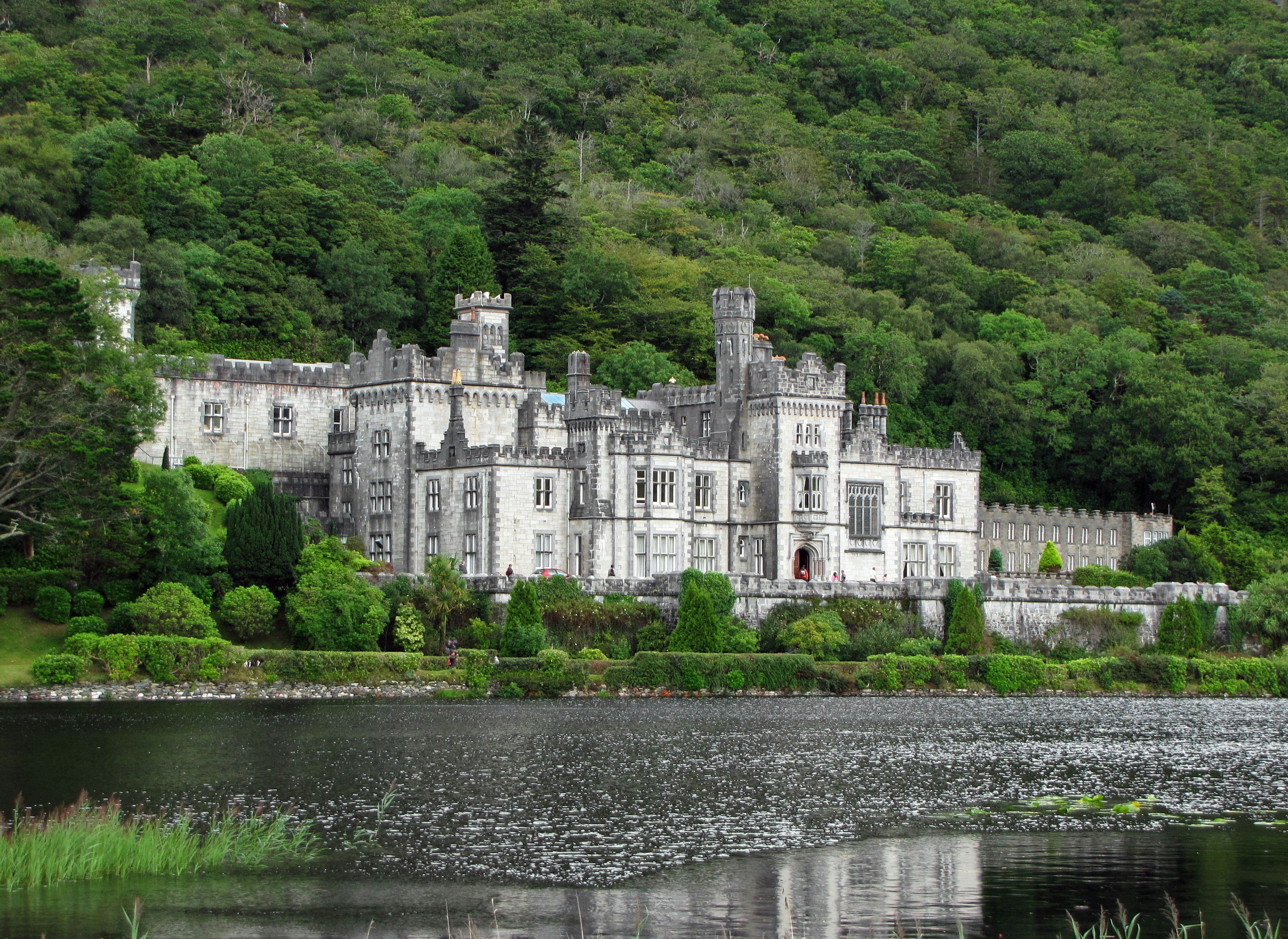 Elegantes Schloss steht vor üppigen grünen Bergen und einem ruhigen See