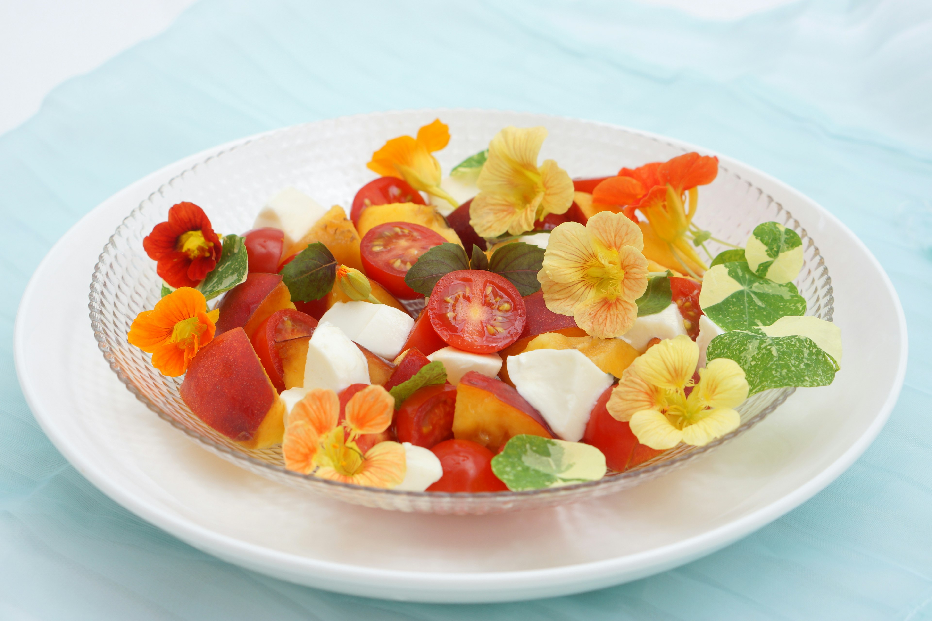 Ensalada colorida con mozzarella y flores comestibles en un plato