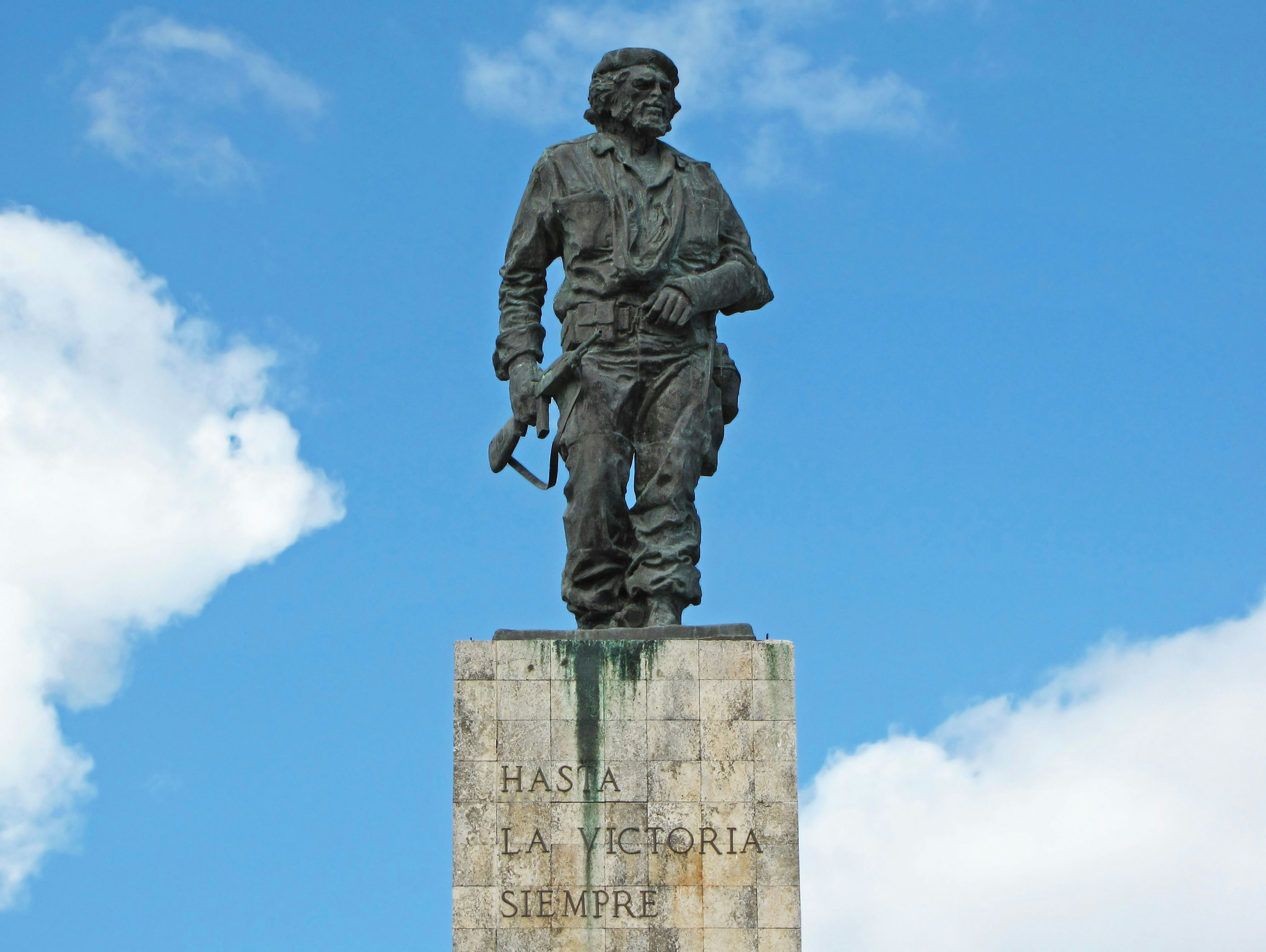 Bronze statue of an armed man standing under a blue sky