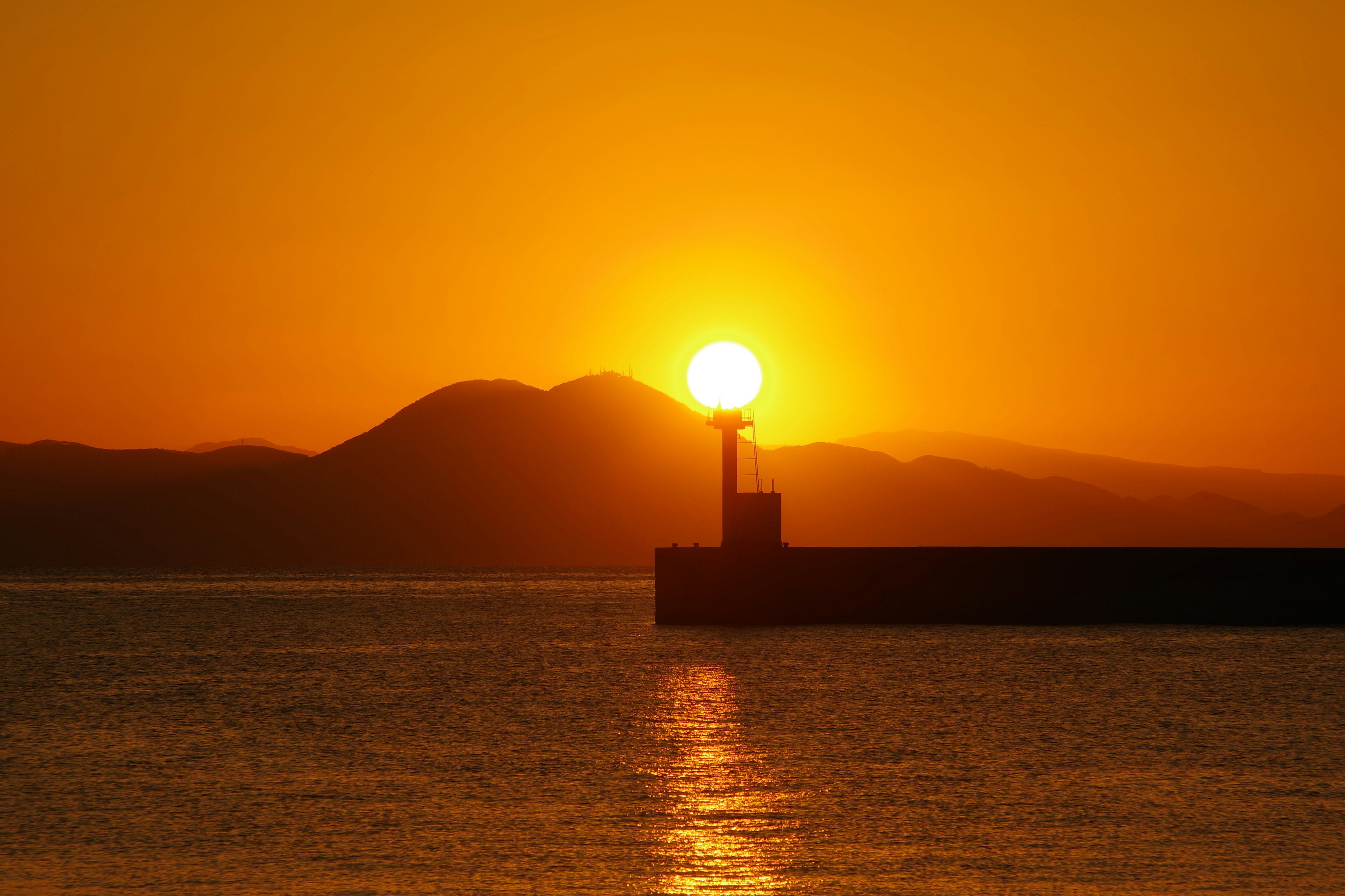 Schöner Sonnenuntergang über dem Ozean mit der Silhouette eines Leuchtturms