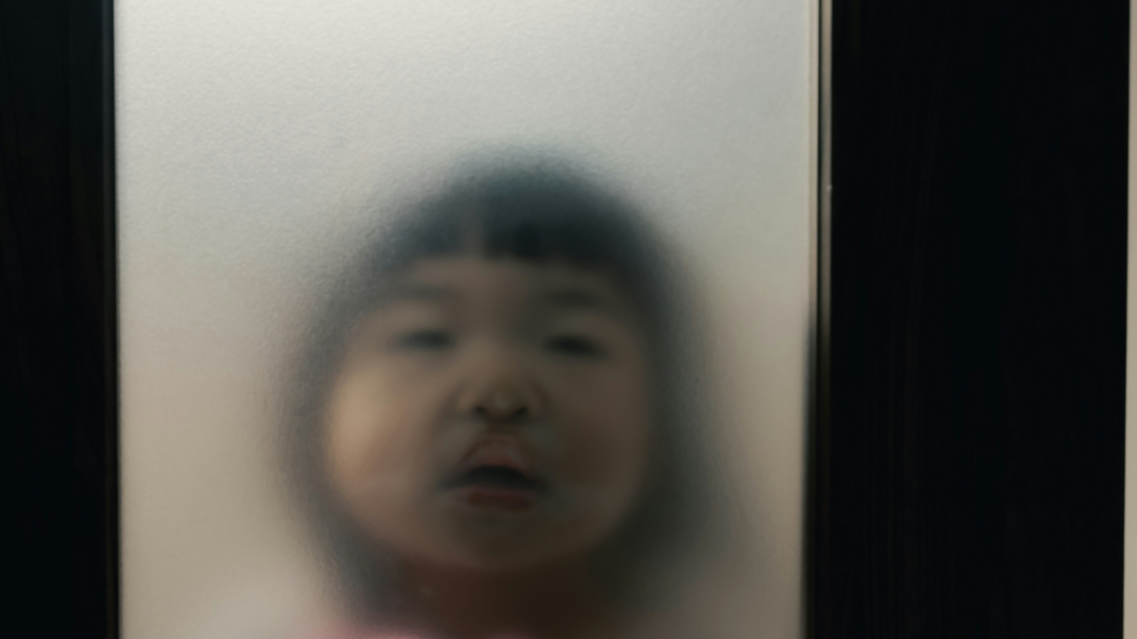 A child's face seen through foggy glass