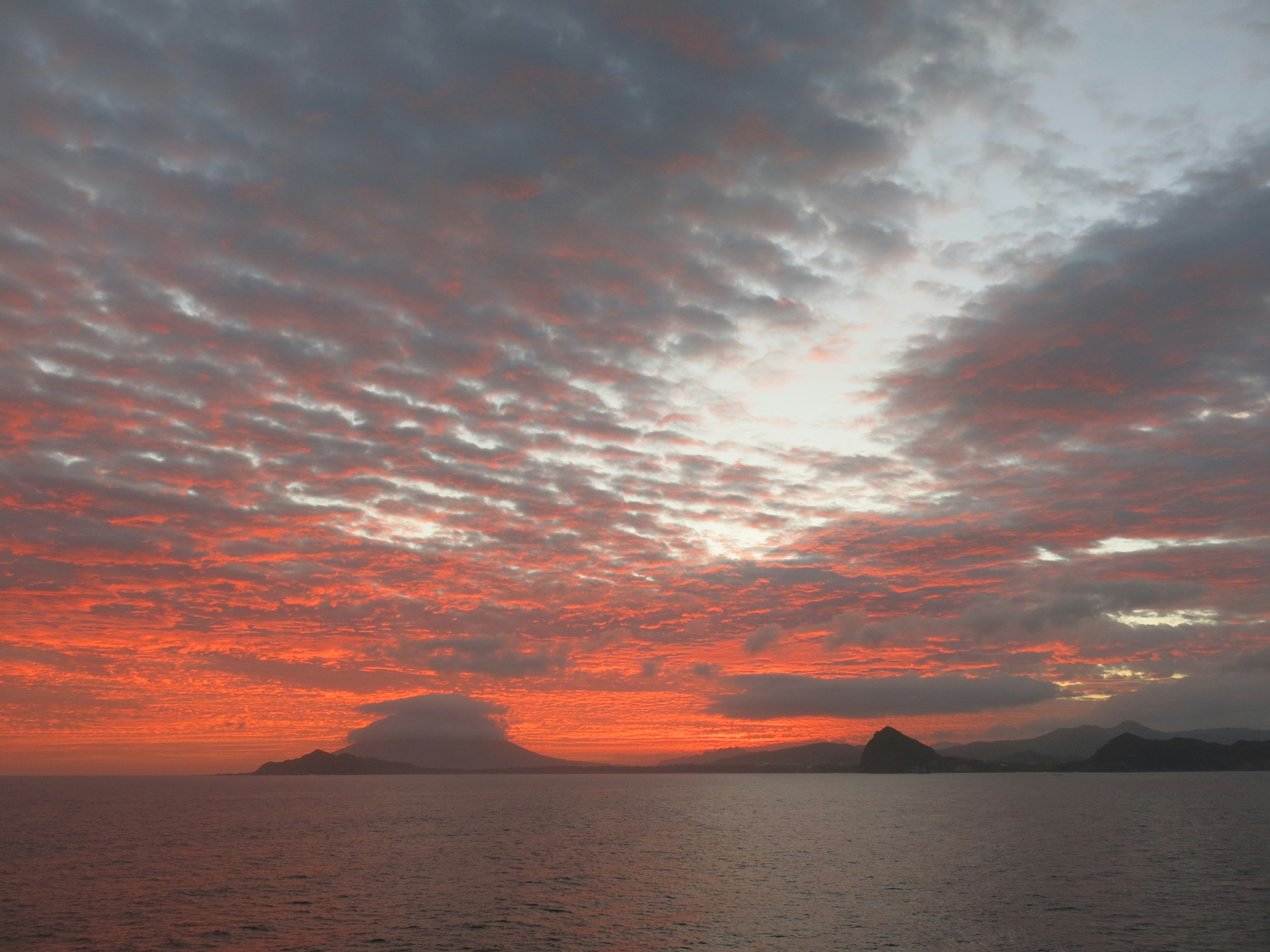 夕焼けの空と海の風景に浮かぶ山々