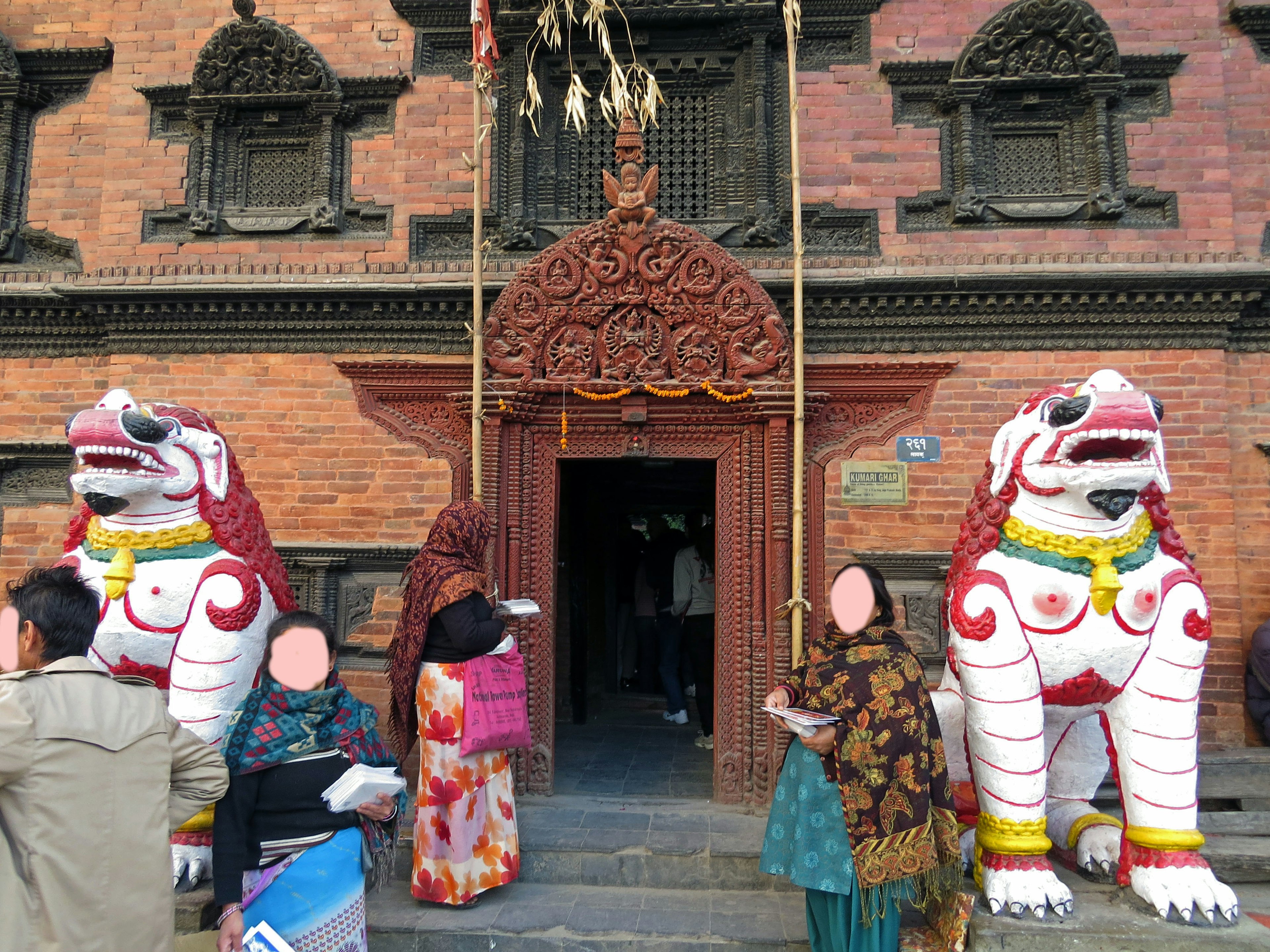 White lion statues at the entrance of a red brick building with visitors