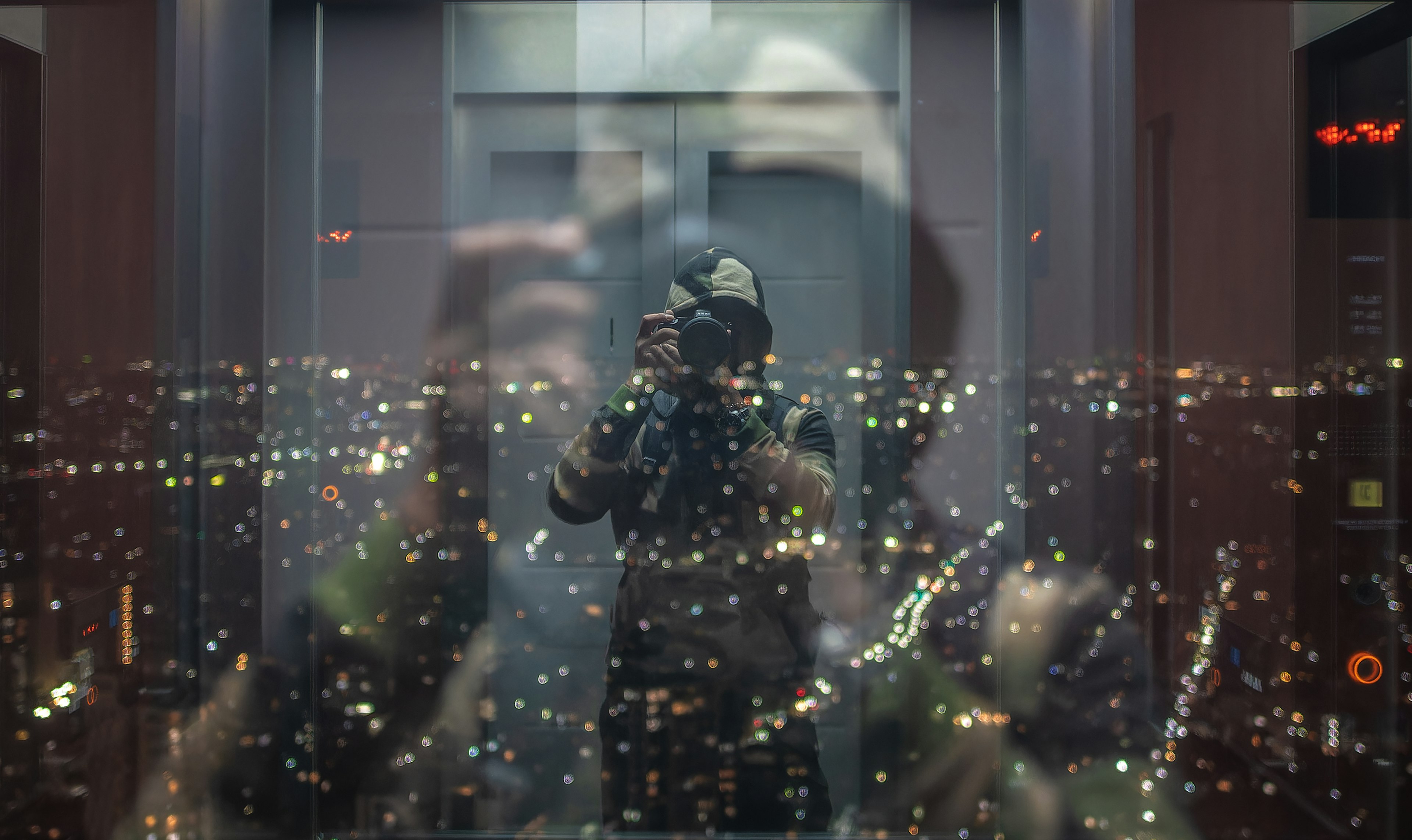 Selbstporträt in einem Aufzug mit Reflexion der Stadtsilhouette bei Nacht