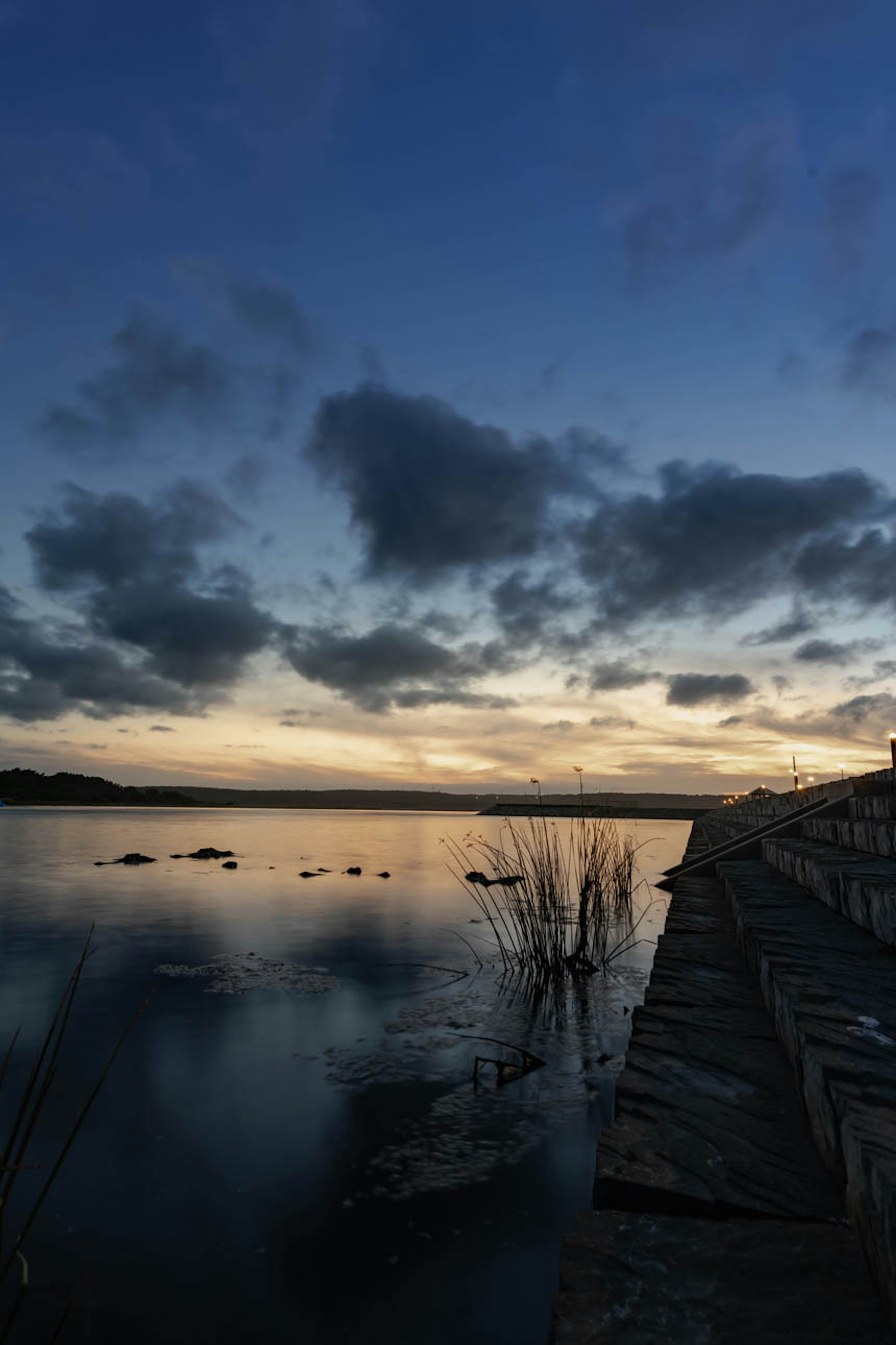 Scène de coucher de soleil au bord du lac avec un ciel nuageux