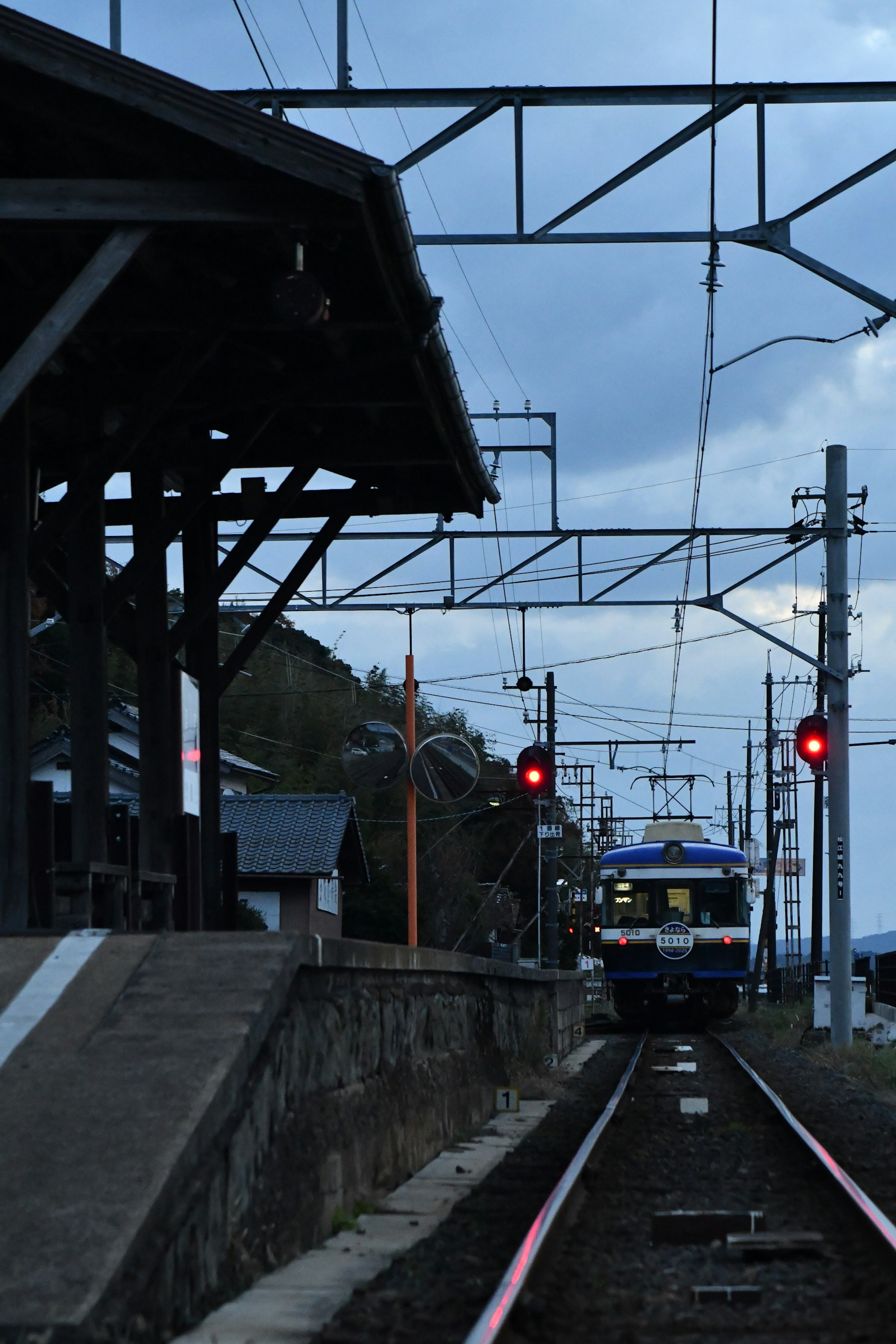 Train stopped at a railway station during twilight with red signals