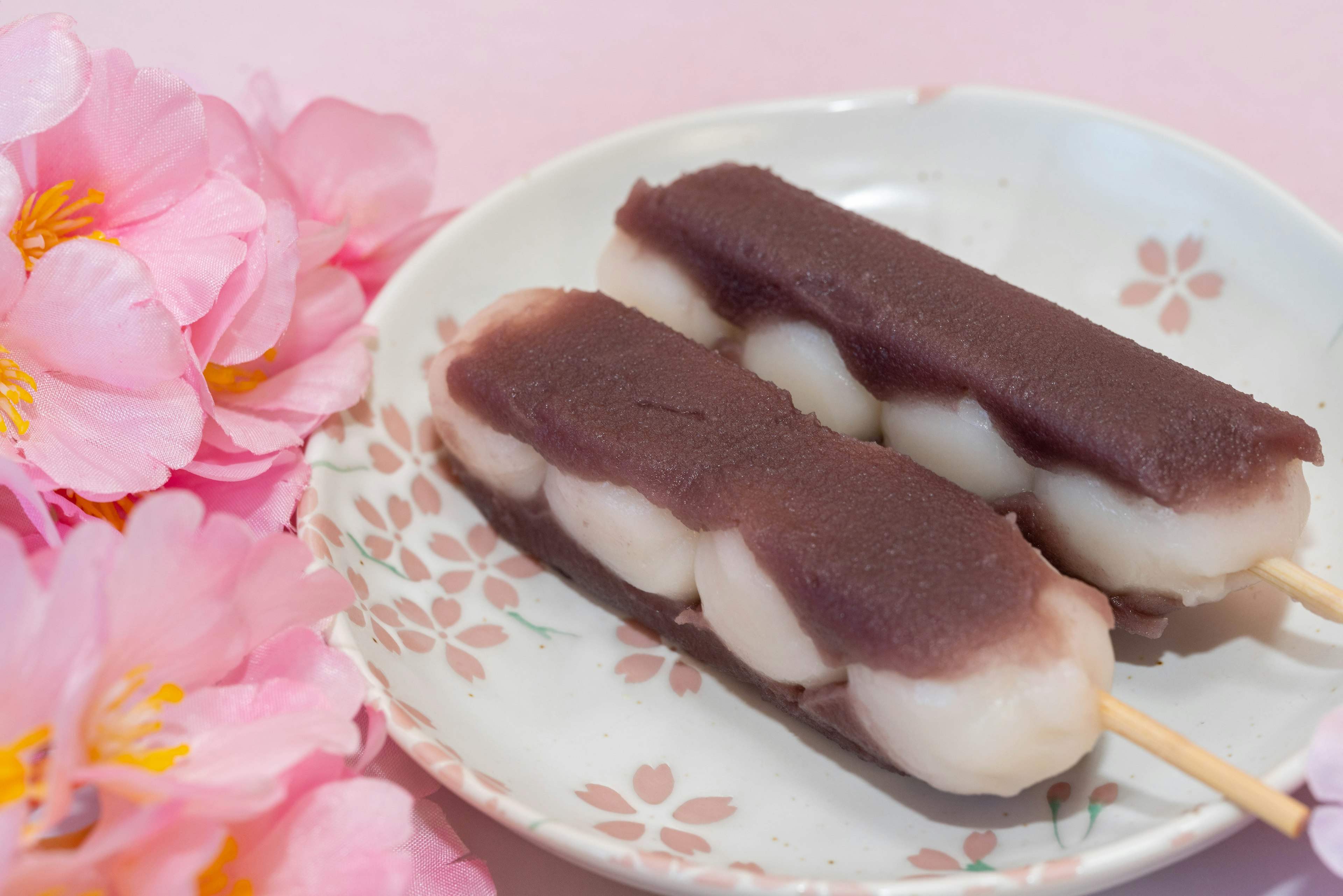 Un plato de brochetas de dango con pasta de frijoles rojos y flores de cerezo