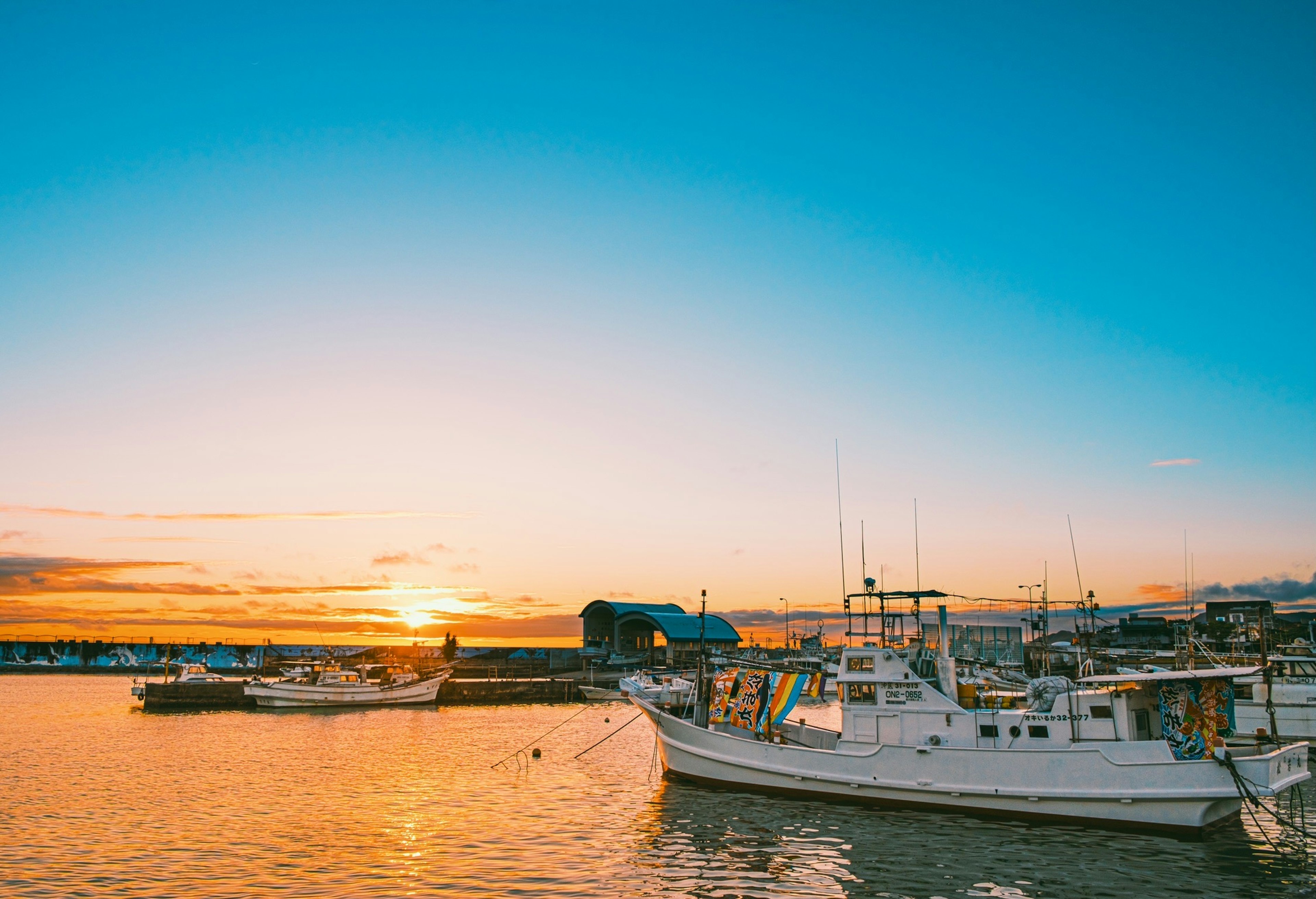 Sonnenuntergang über dem Meer mit weißen Booten im Hafen