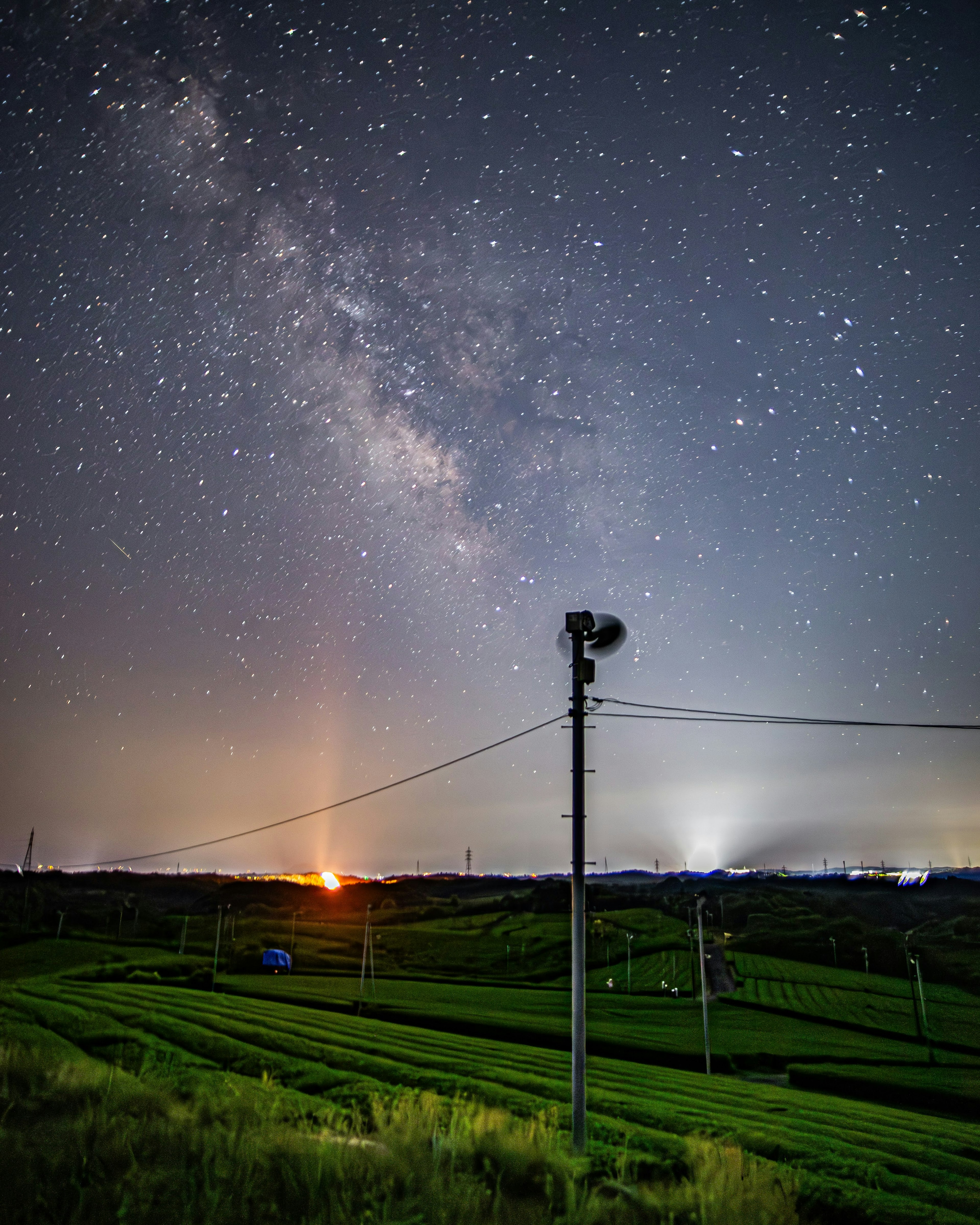 星空の下で見える田園風景と電柱