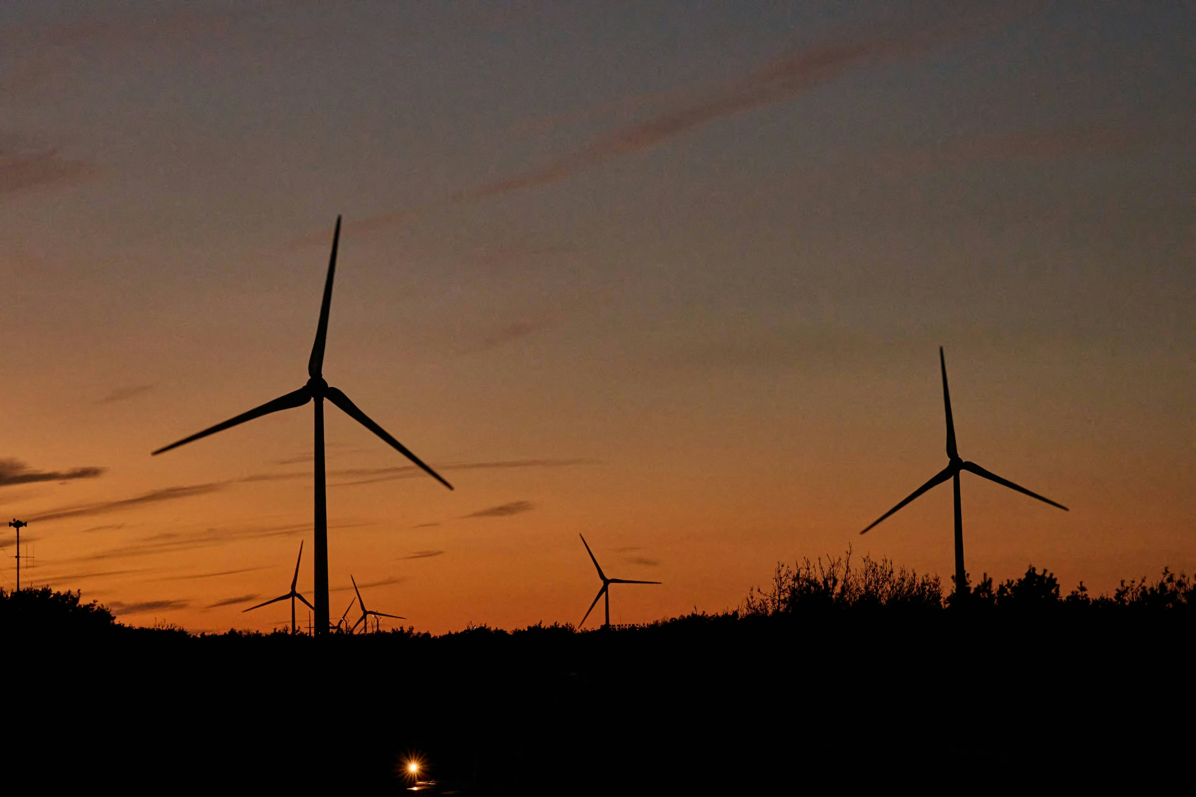 Silhouetted wind turbines against a sunset sky