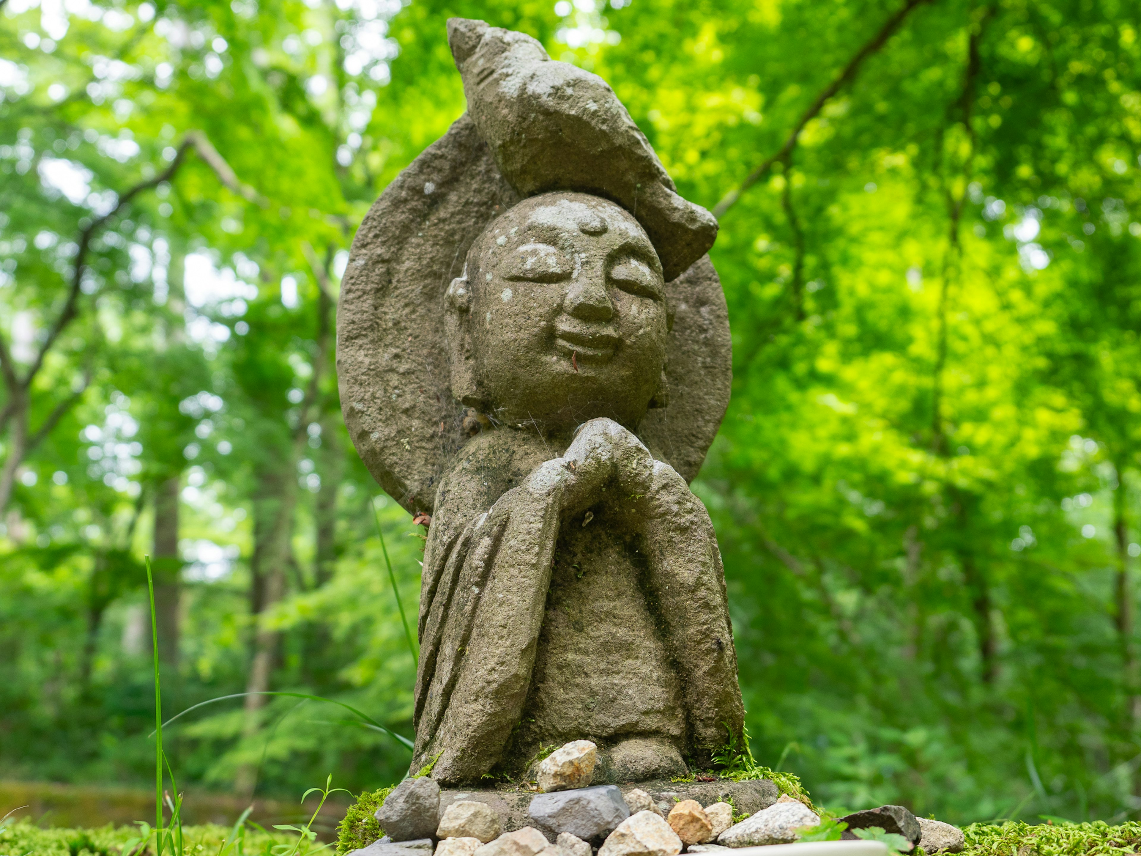 Estatua de piedra sonriendo en un bosque verde