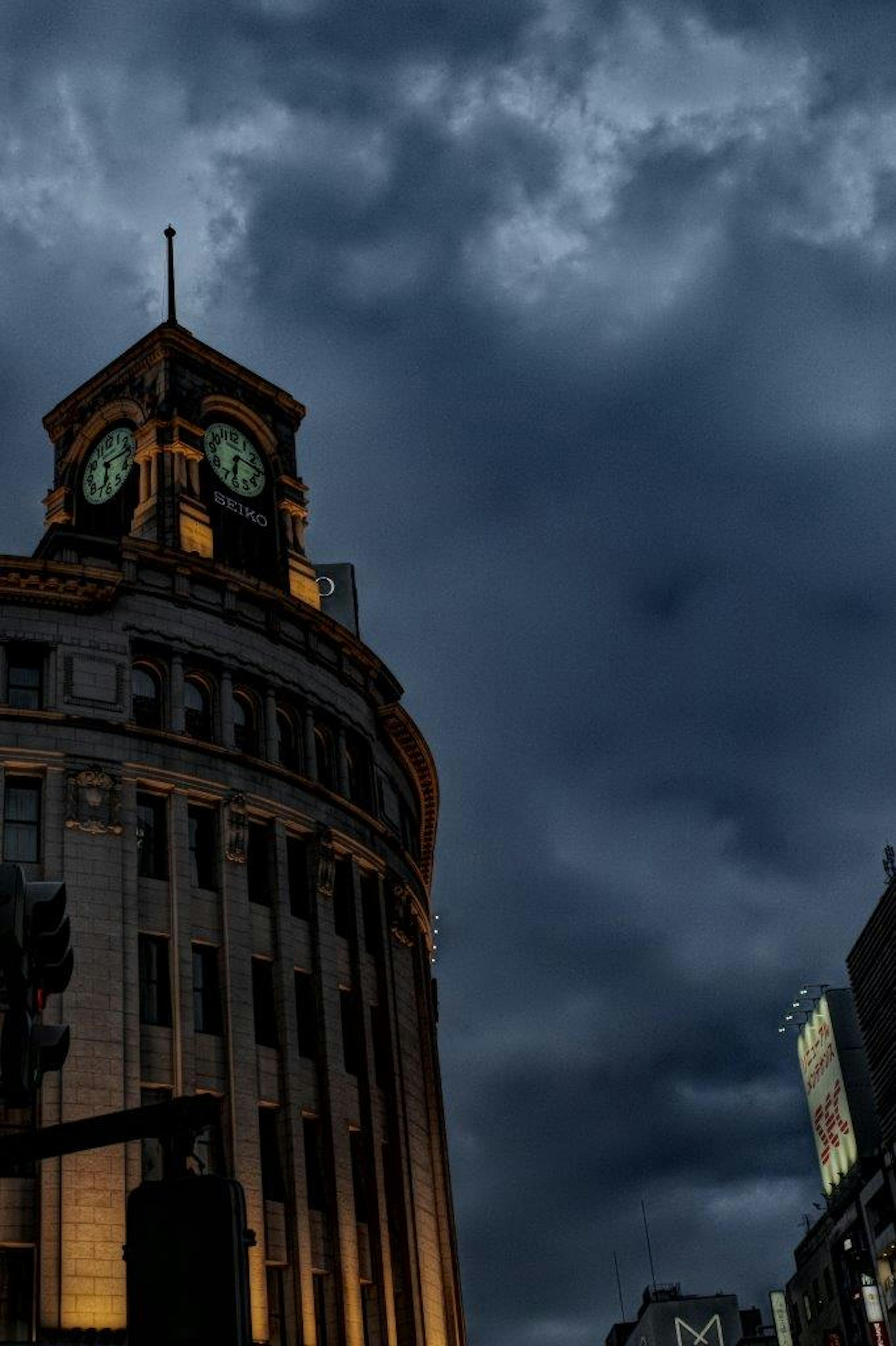 暗い雲の下にある時計塔のある建物の夜景