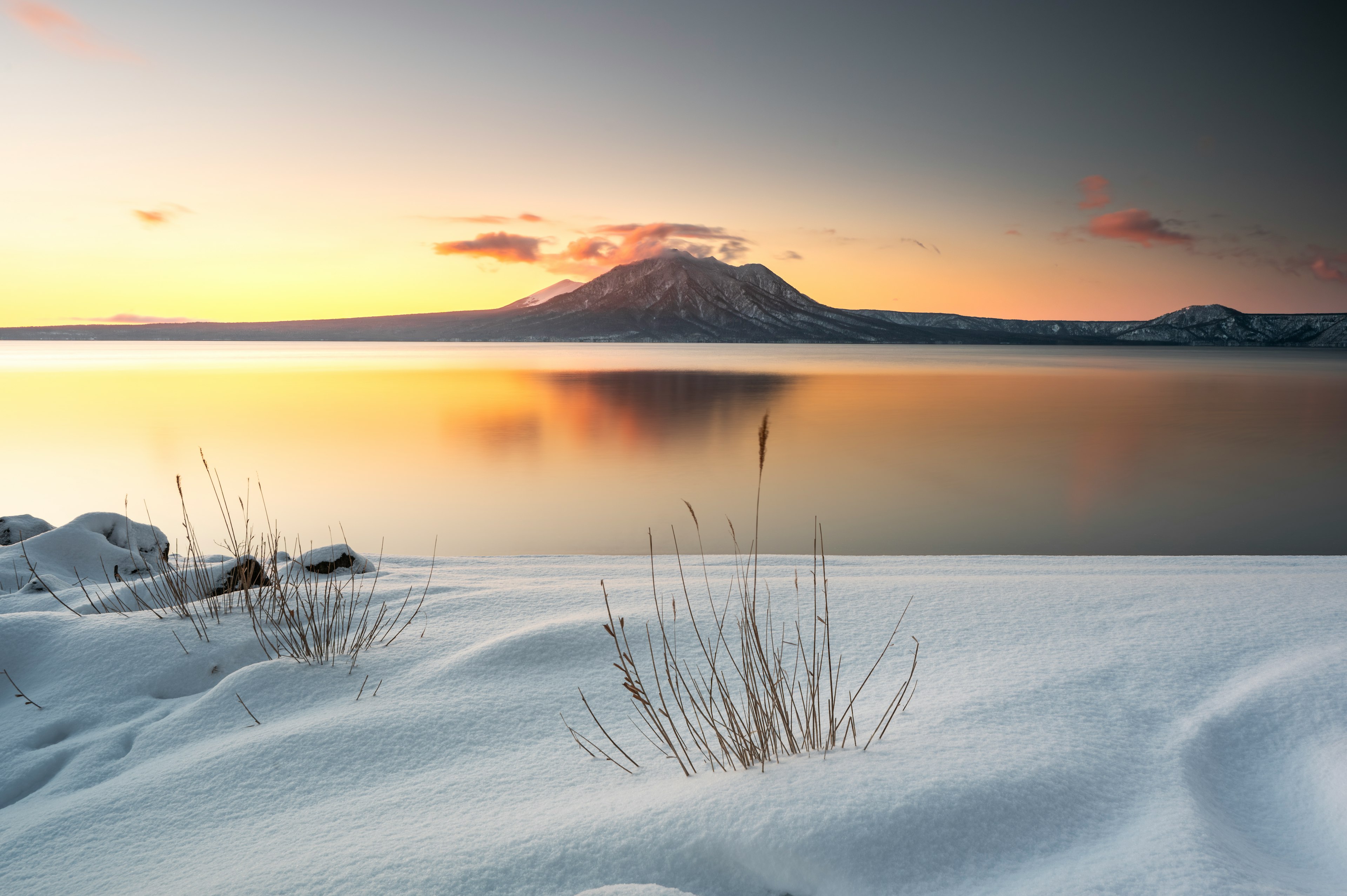 雪に覆われた風景と湖の美しい夕焼けと山