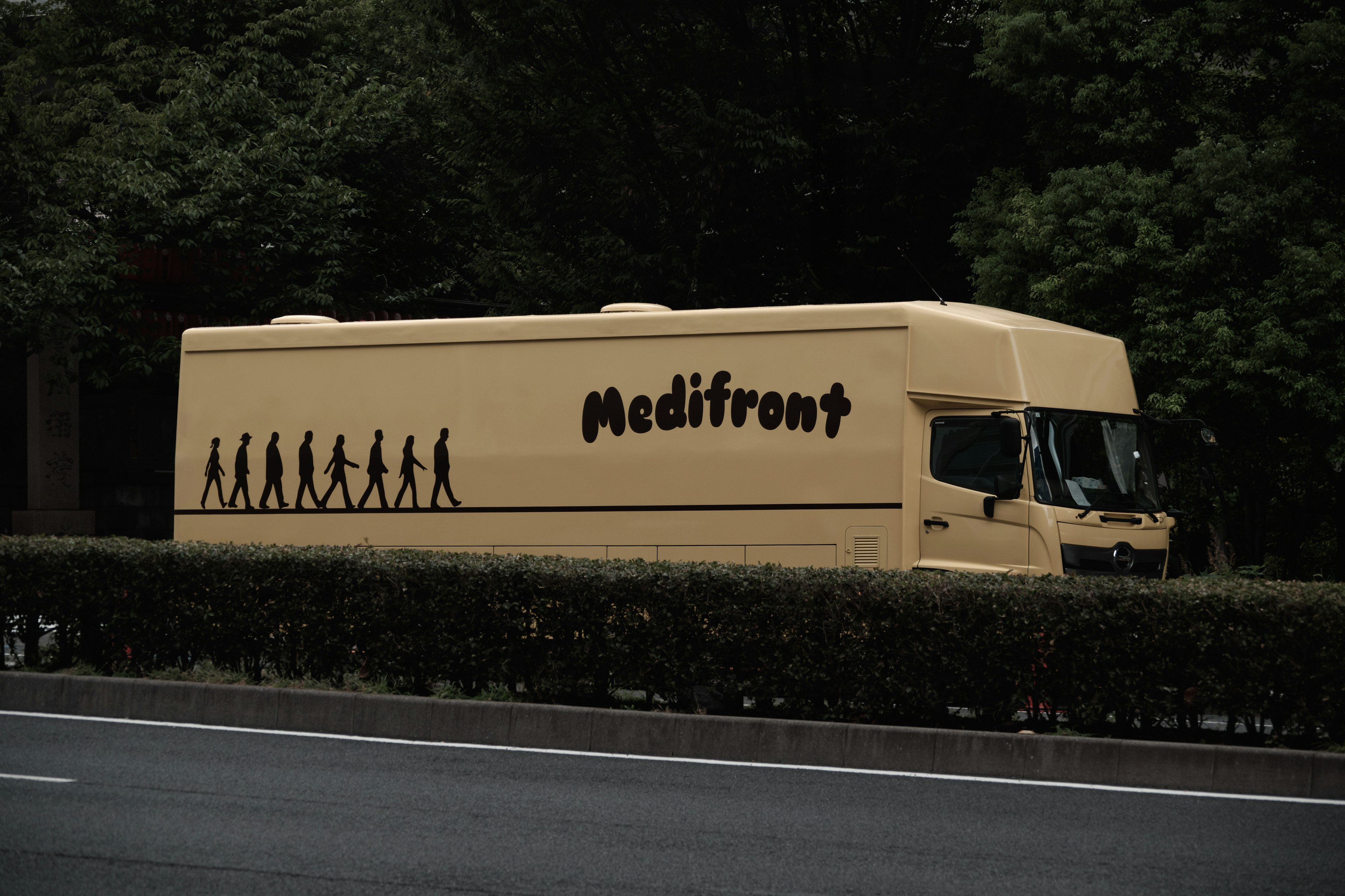 Un camion Medifront garé au bord de la route avec des silhouettes de l'évolution humaine